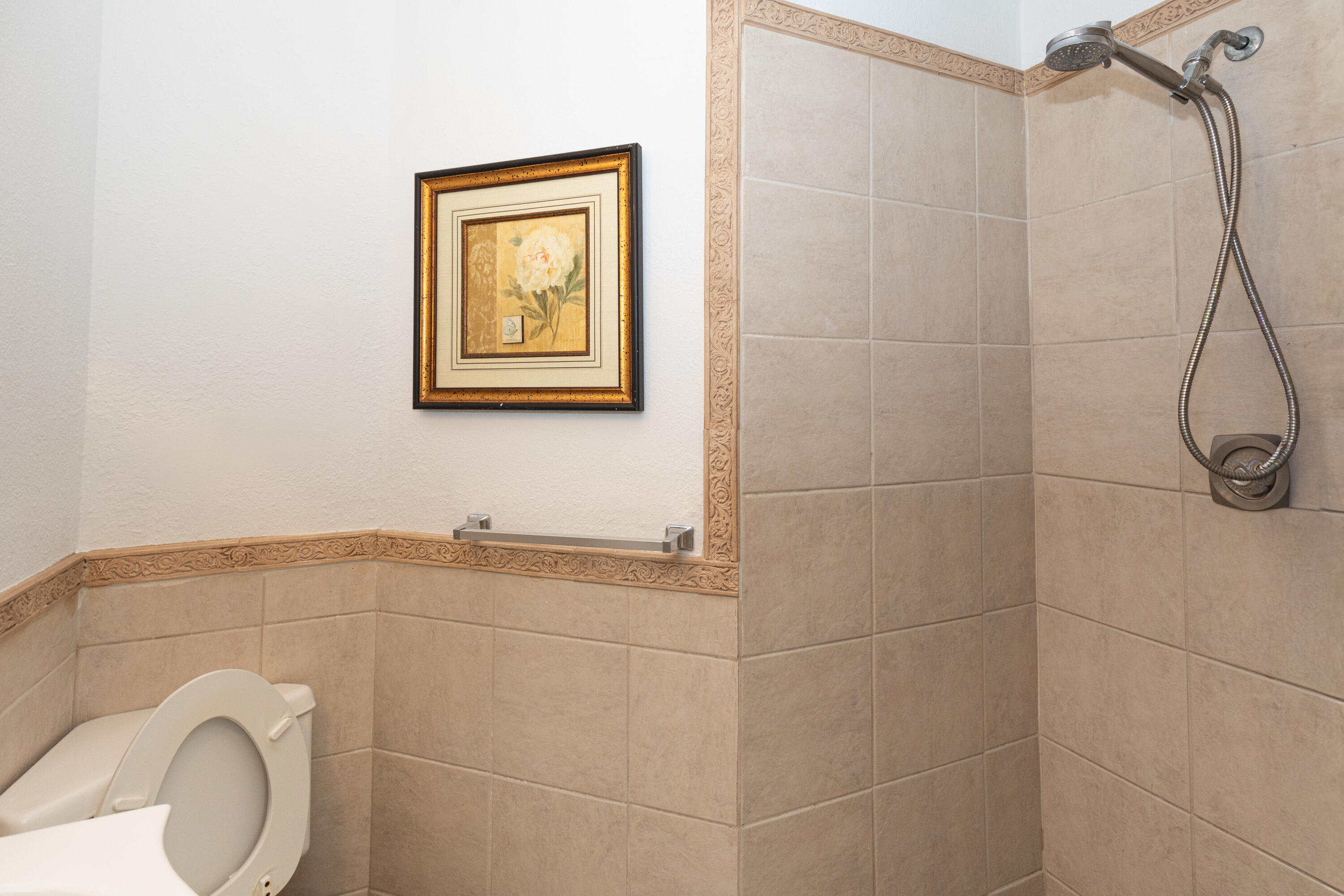 Tiled shower stall with a brushed nickel shower head and hand-held sprayer