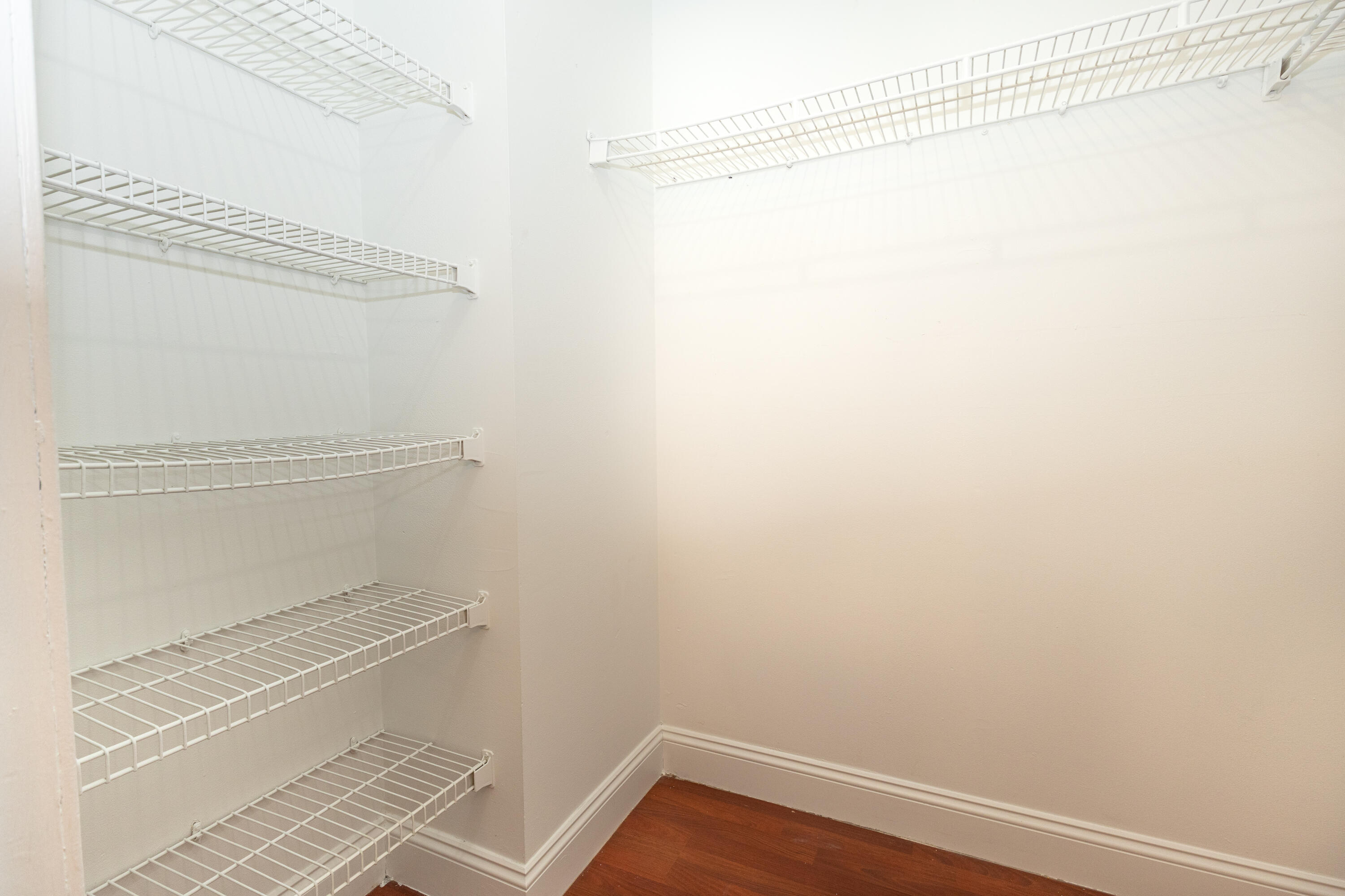 White wire shelving, white painted walls, wood-finish flooring, and white trim