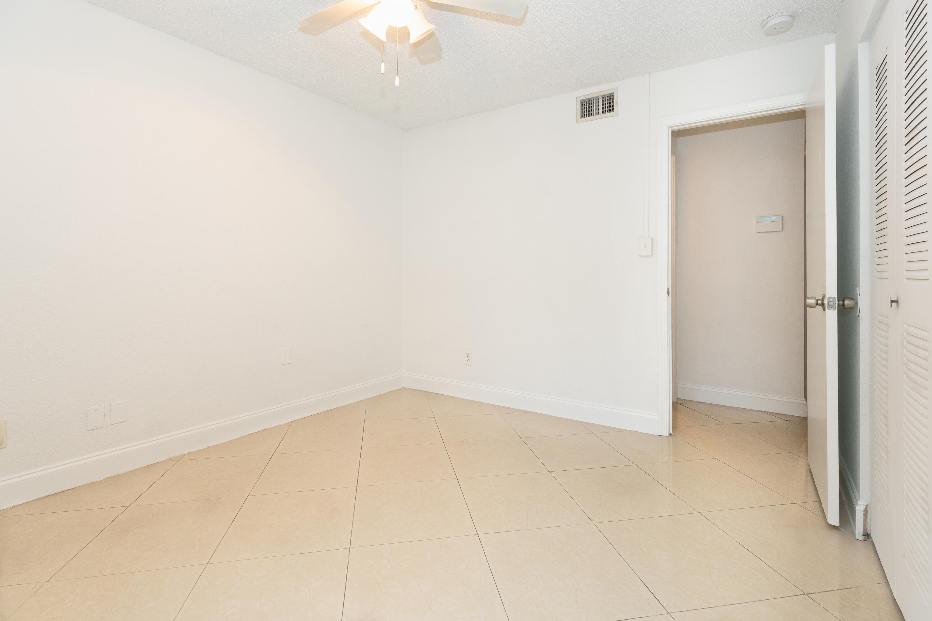 Spacious room featuring tile flooring throughout, ceiling fan with integrated lighting, and generous wall space