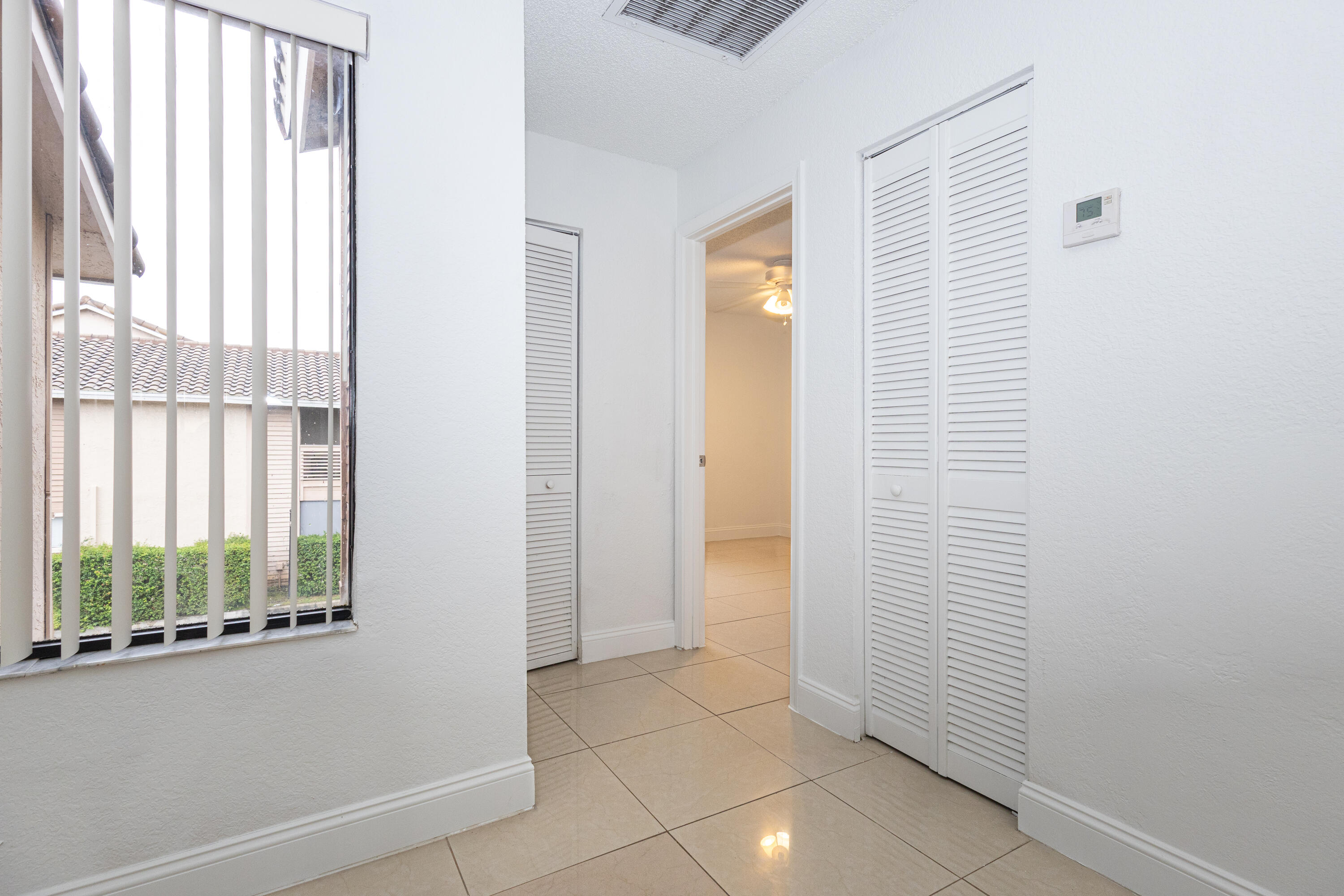 Bright, open entryway featuring tile flooring, white louvered closet doors, security gate access, and abundant natural light from street-facing window Bright, open entryway featuring tile flooring, white louvered closet doors, security gate access, and abundant natural light from street-facing window