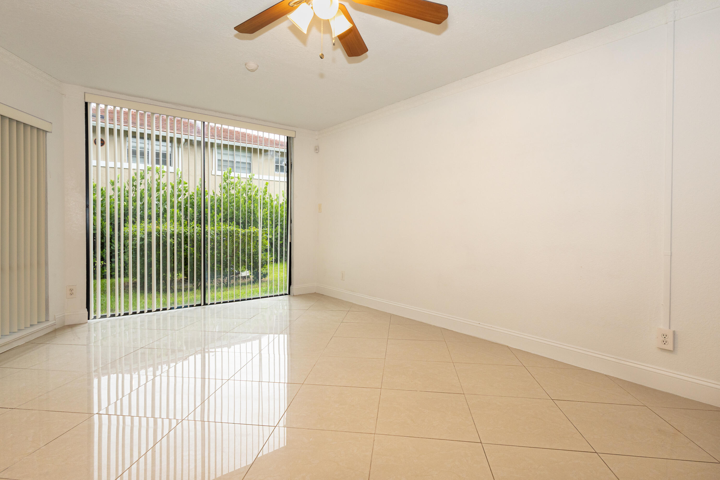 Glossy tiled flooring, large sliding glass doors, vertical blinds, and a ceiling fan Glossy tiled flooring, large sliding glass doors, vertical blinds, and a ceiling fan