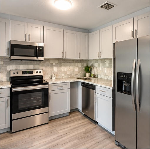 Kitchen featuring shaker-style cabinetry, stainless steel appliances, speckled stone-finish countertops, tile backsplash, and wood-finish flooring