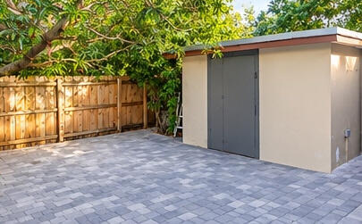 Paver patio area with a detached storage structure and wood-panel fencing