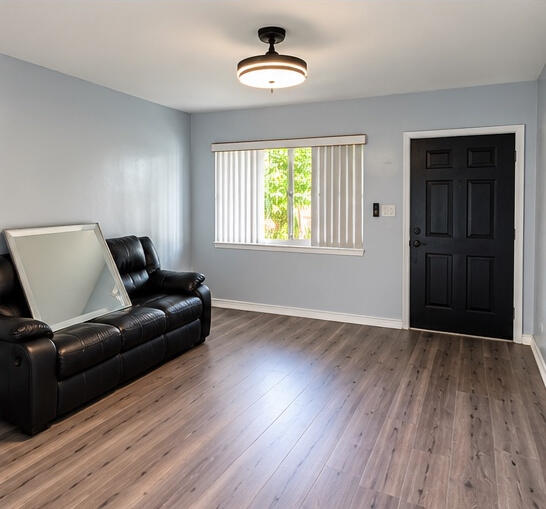 Wood-finish flooring, matte black entry door, semi-flush mount drum light fixture, and horizontal window with vertical blinds
