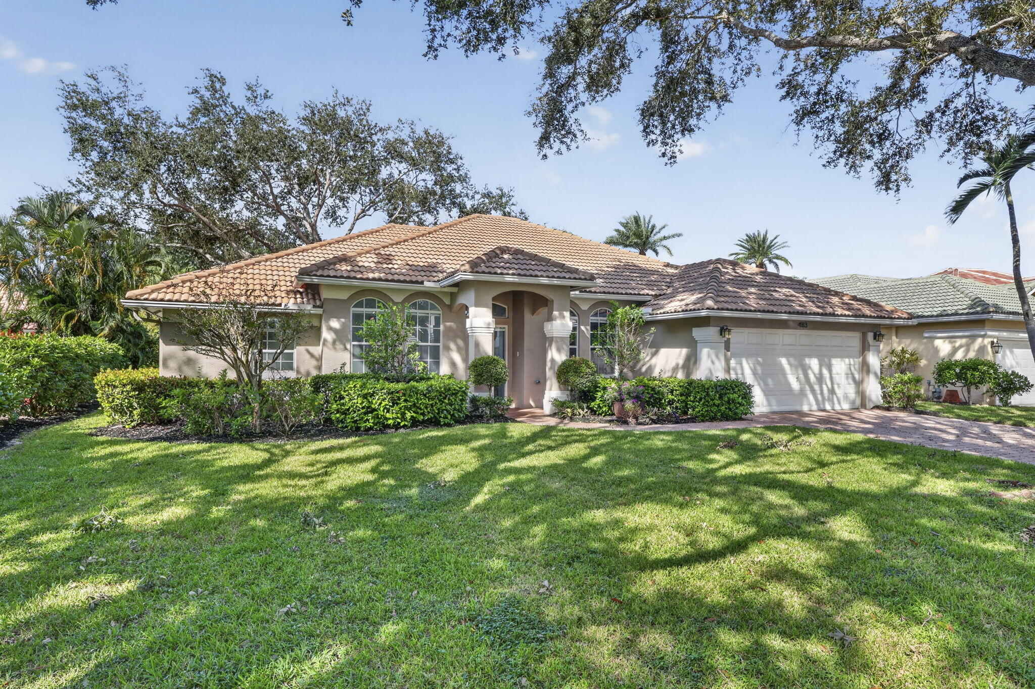 Stucco exterior featuring a clay tile roof, arched windows, covered entryway with decorative columns, and an attached multi-car garage Stucco exterior featuring a clay tile roof, arched windows, covered entryway with decorative columns, and an attached multi-car garage