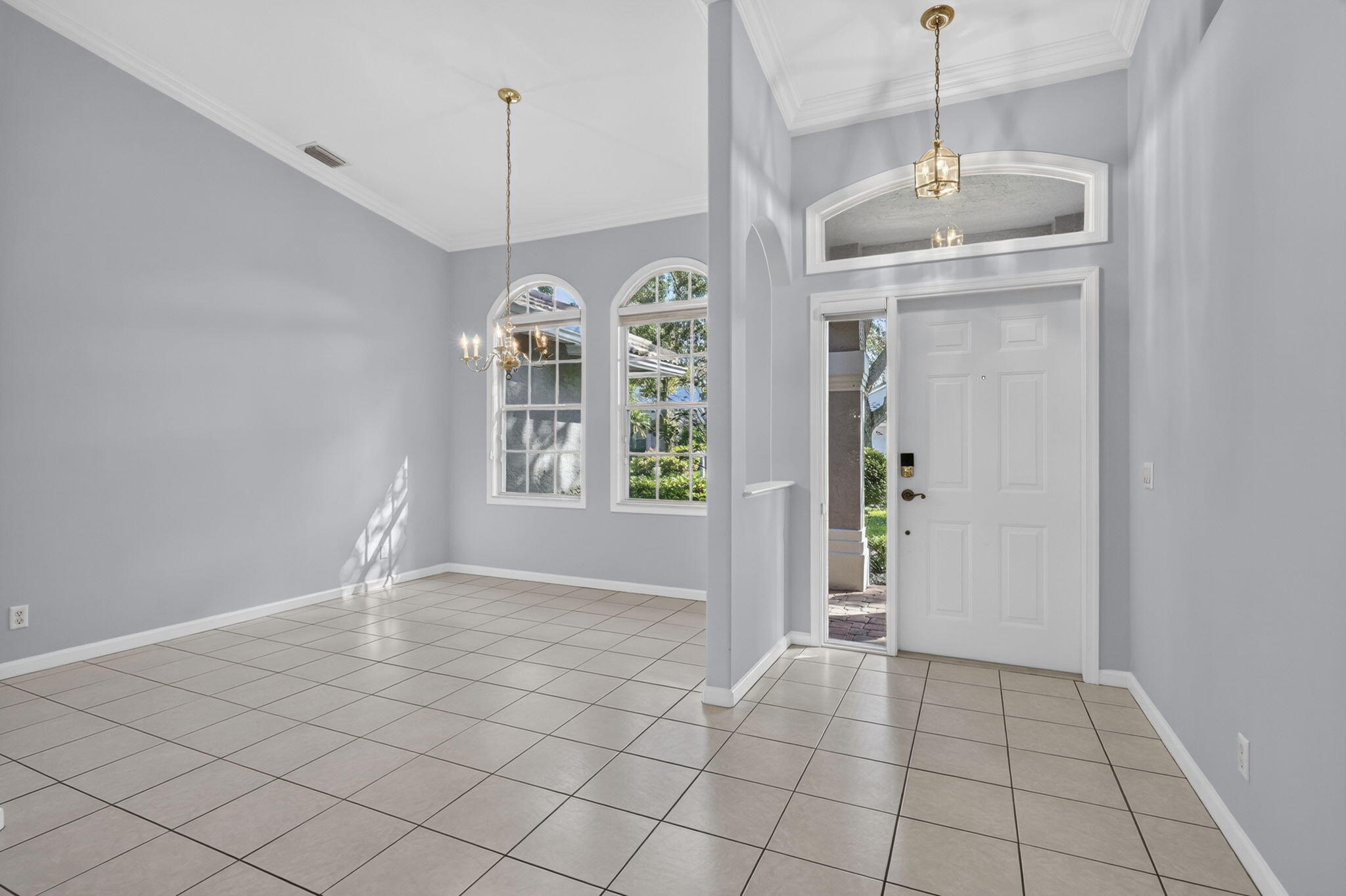 Entrance foyer and surrounding area featuring vaulted ceilings, arched windows, tile flooring, and decorative hanging light fixtures