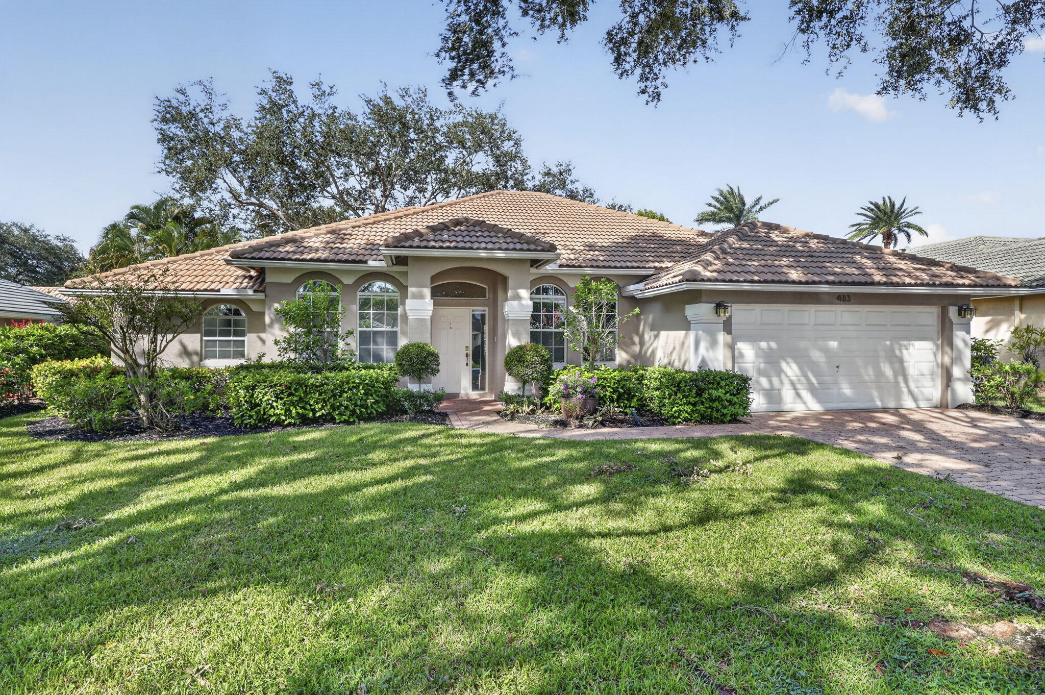 Single-story residence featuring a tile roof, arched windows, covered entryway, and a brick-paver driveway Single-story residence featuring a tile roof, arched windows, covered entryway, and a brick-paver driveway