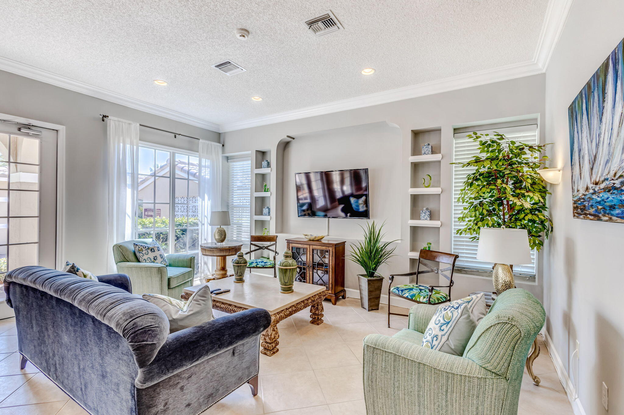 Living area featuring tile flooring, recessed lighting, crown molding, and two sets of symmetrical built-in display shelving flanking a central media niche