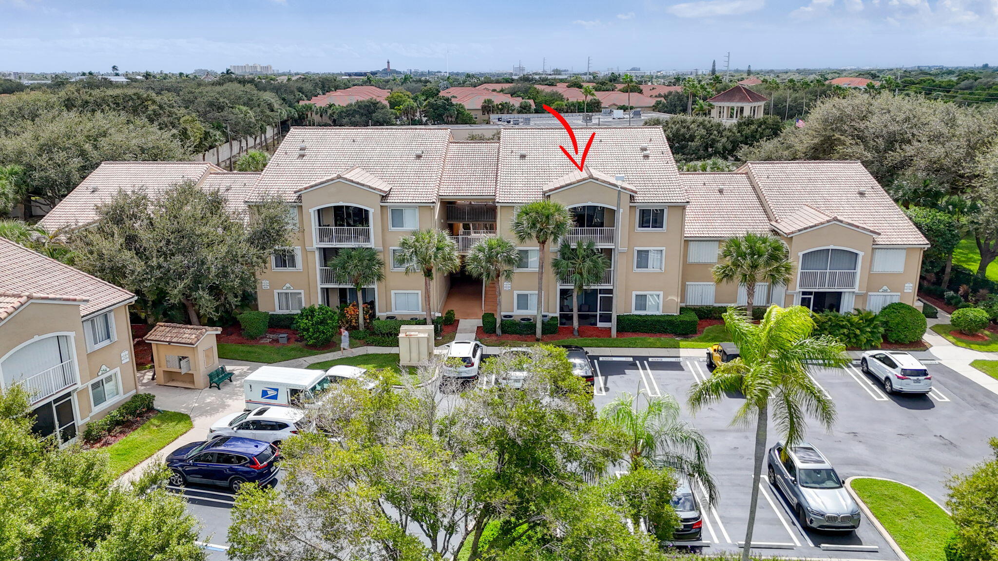 Multi-story building with tile roof, screened-in balconies, and dedicated surface parking