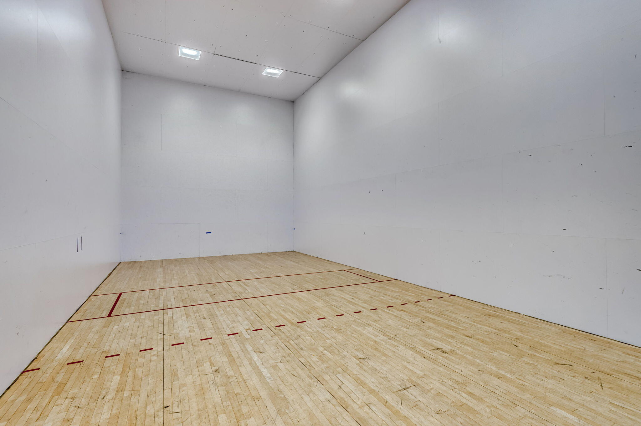 Indoor court featuring wood-finish flooring, high-impact paneled walls, and recessed ceiling lighting