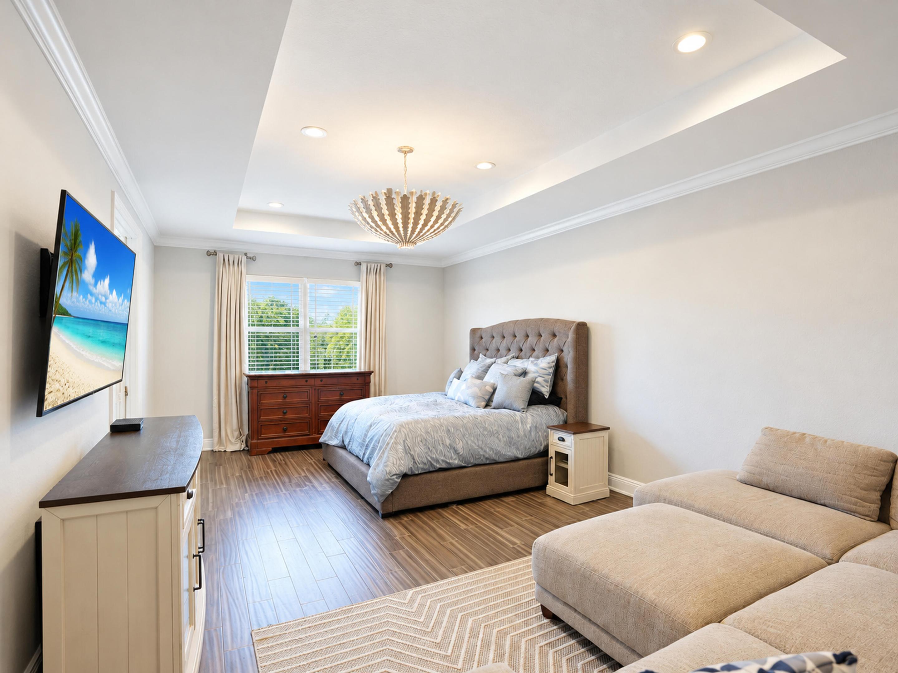 Tray ceiling with recessed lighting, wood-finish flooring, and crown molding