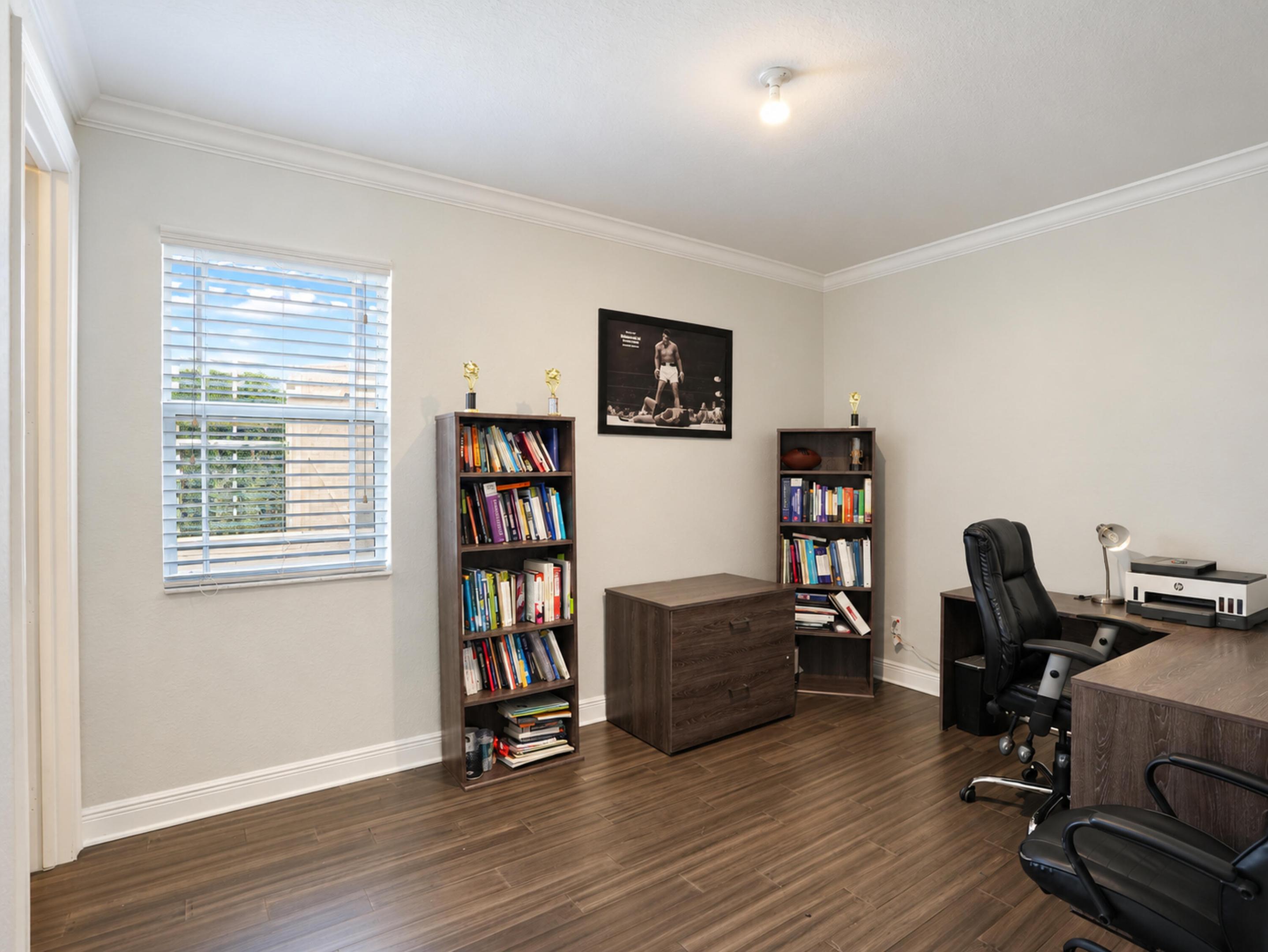 Wood-finish flooring, neutral wall tones, crown molding, and a single-pane window with horizontal blinds