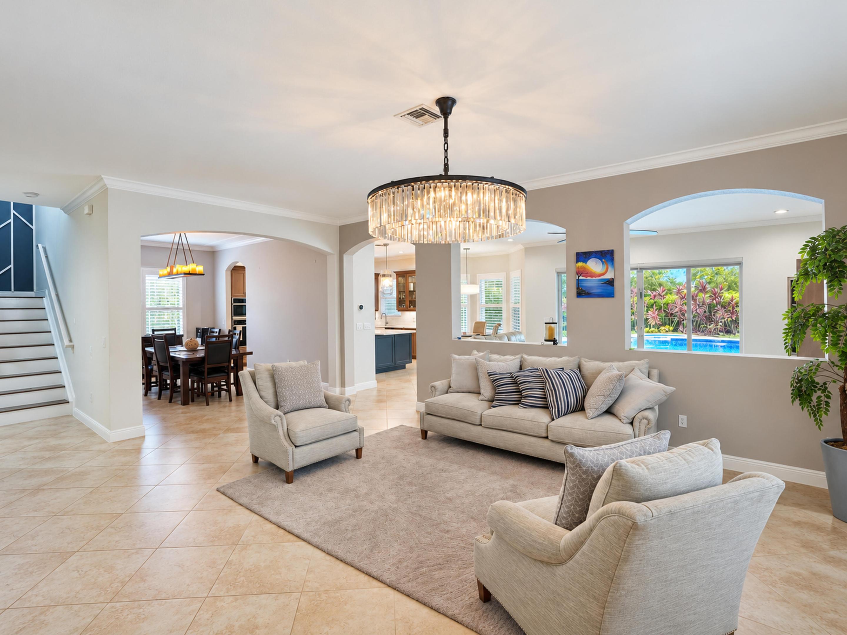 Open floor plan featuring tile flooring, arched wall openings, crown molding, and a tiered crystal chandelier