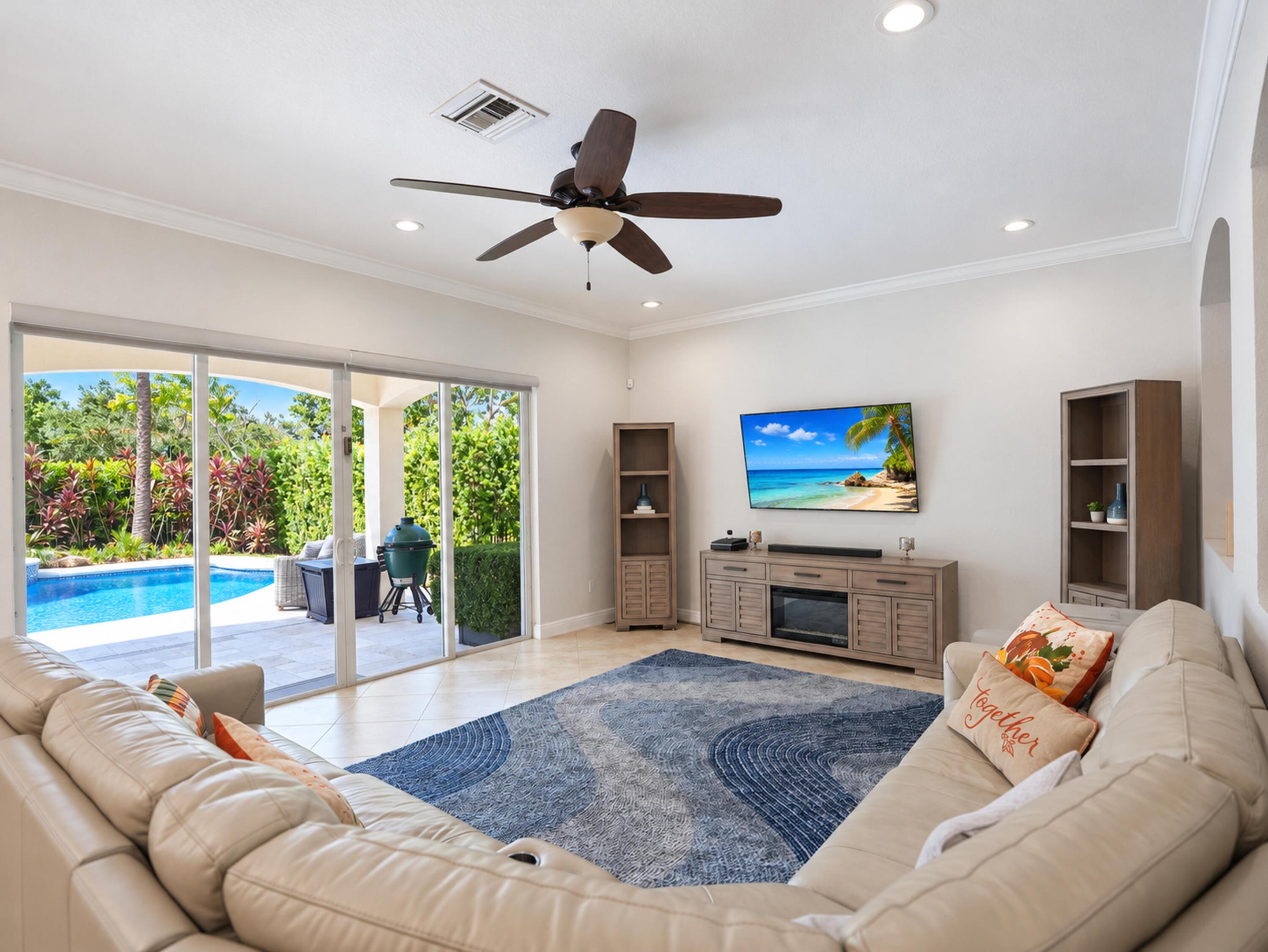 Living area featuring large sliding glass doors, neutral tile flooring, recessed lighting, crown molding, and a ceiling fan
