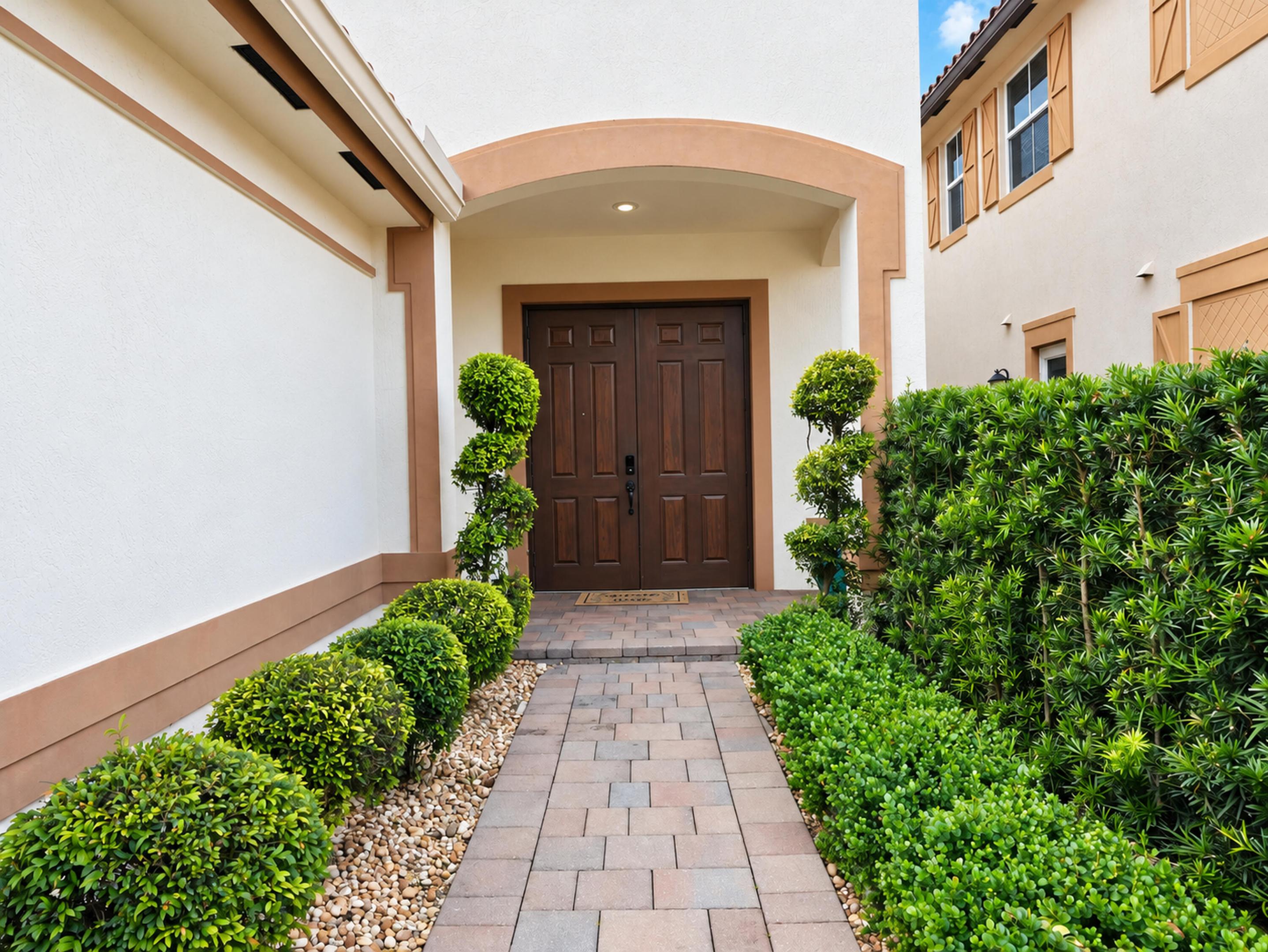 Stucco exterior entryway featuring a double-door entry, arched portico, and paver walkway