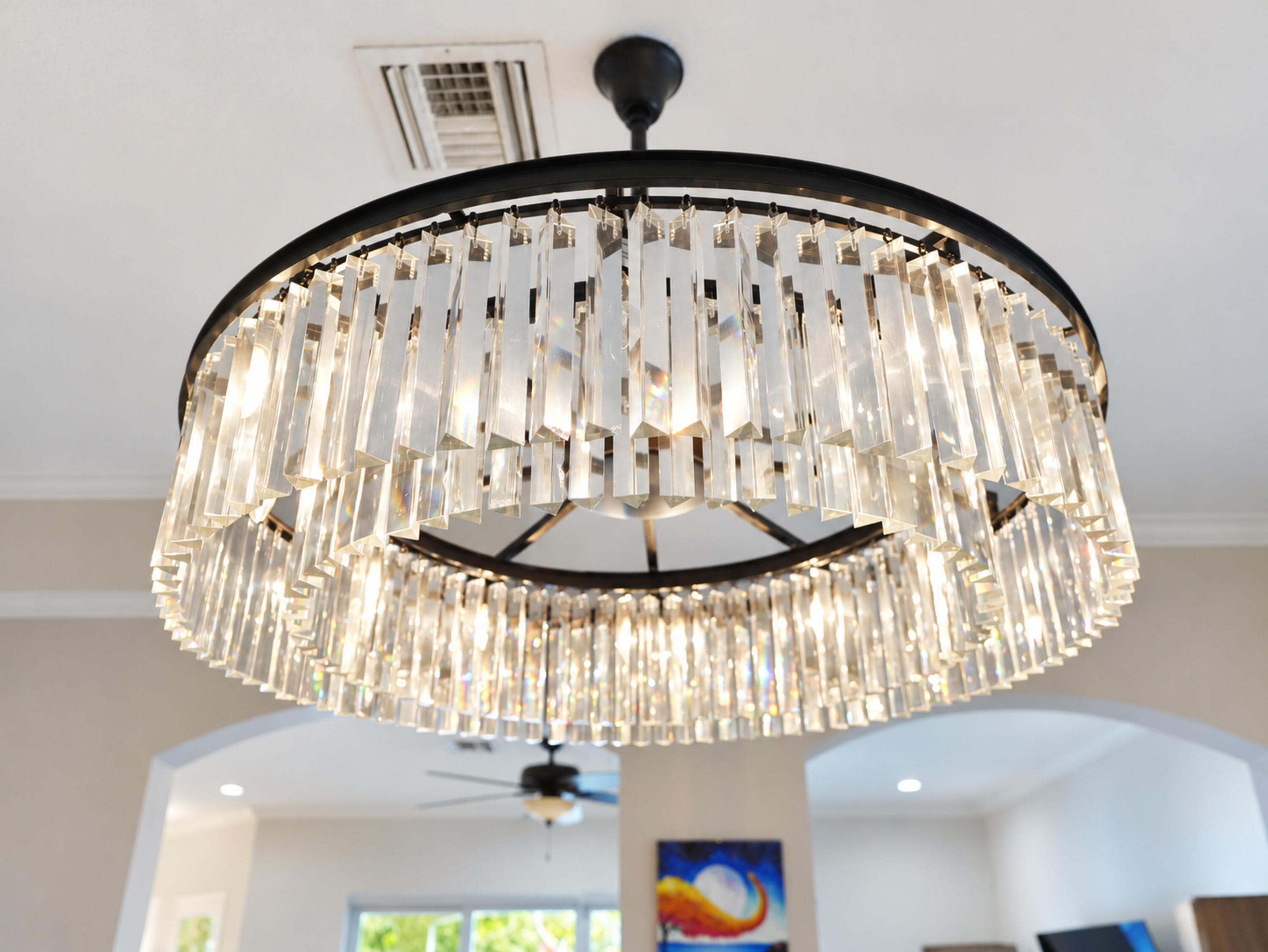 Circular chandelier featuring tiered, vertical clear glass prisms set in a black metal frame