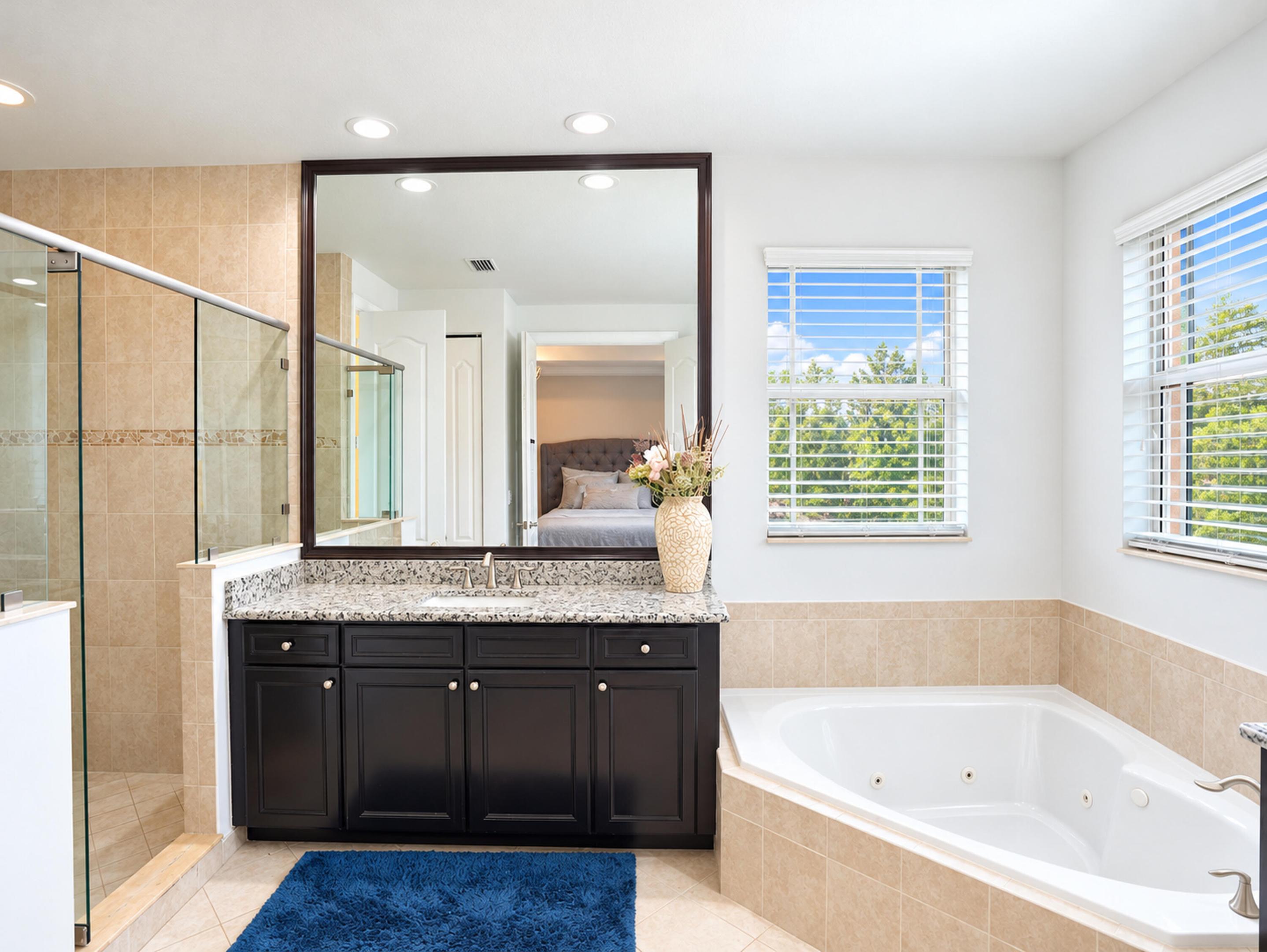 Bathroom featuring a dark wood vanity with stone-finish countertop, walk-in shower with a glass enclosure, jetted soaking tub, recessed lighting, and tile flooring