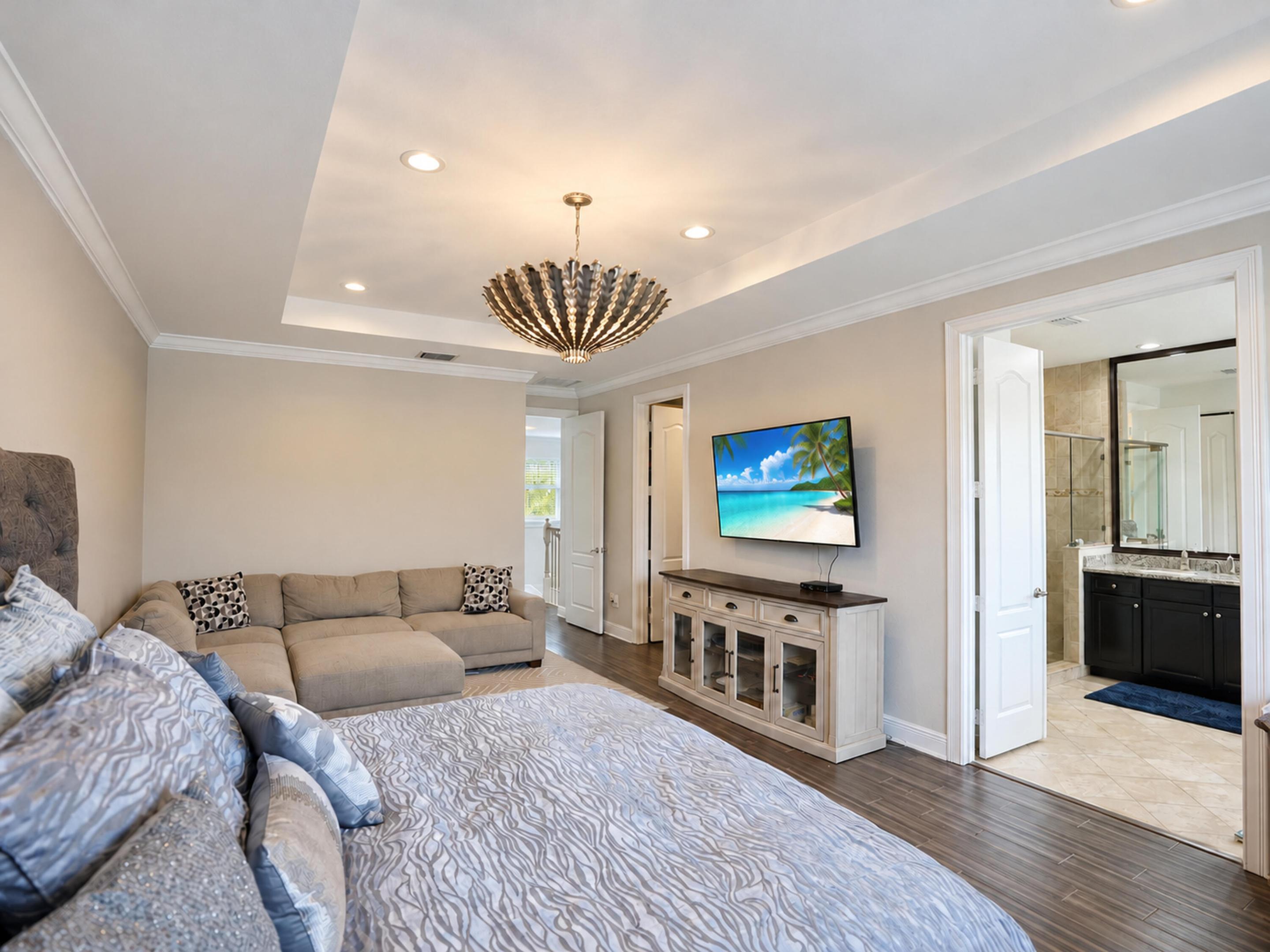 Tray ceiling with recessed lighting, statement chandelier (excluded), wood-finish flooring, and crown molding