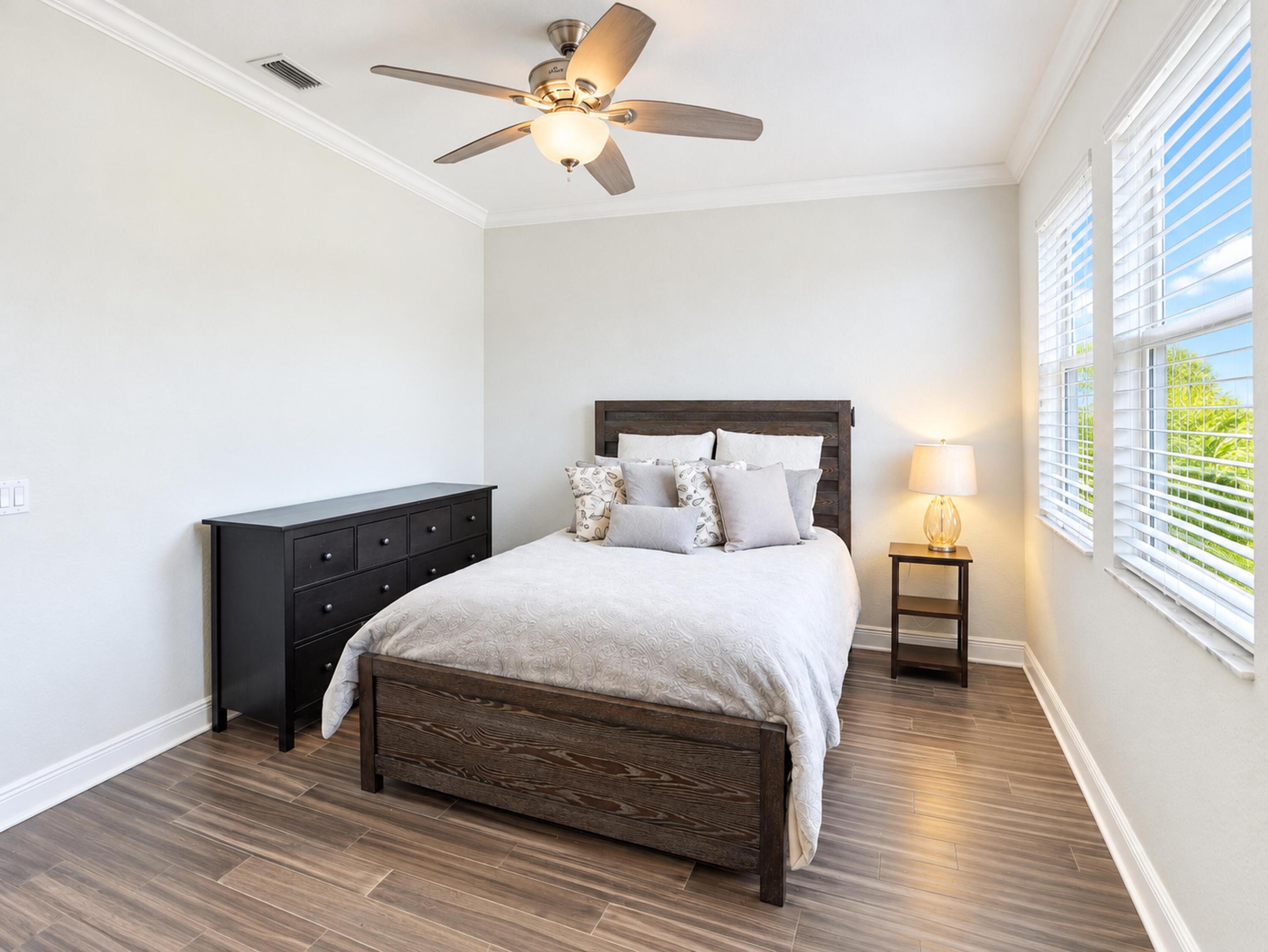 Wood-finish flooring, crown molding, multi-pane windows with horizontal blinds, and a central ceiling fan with integrated lighting