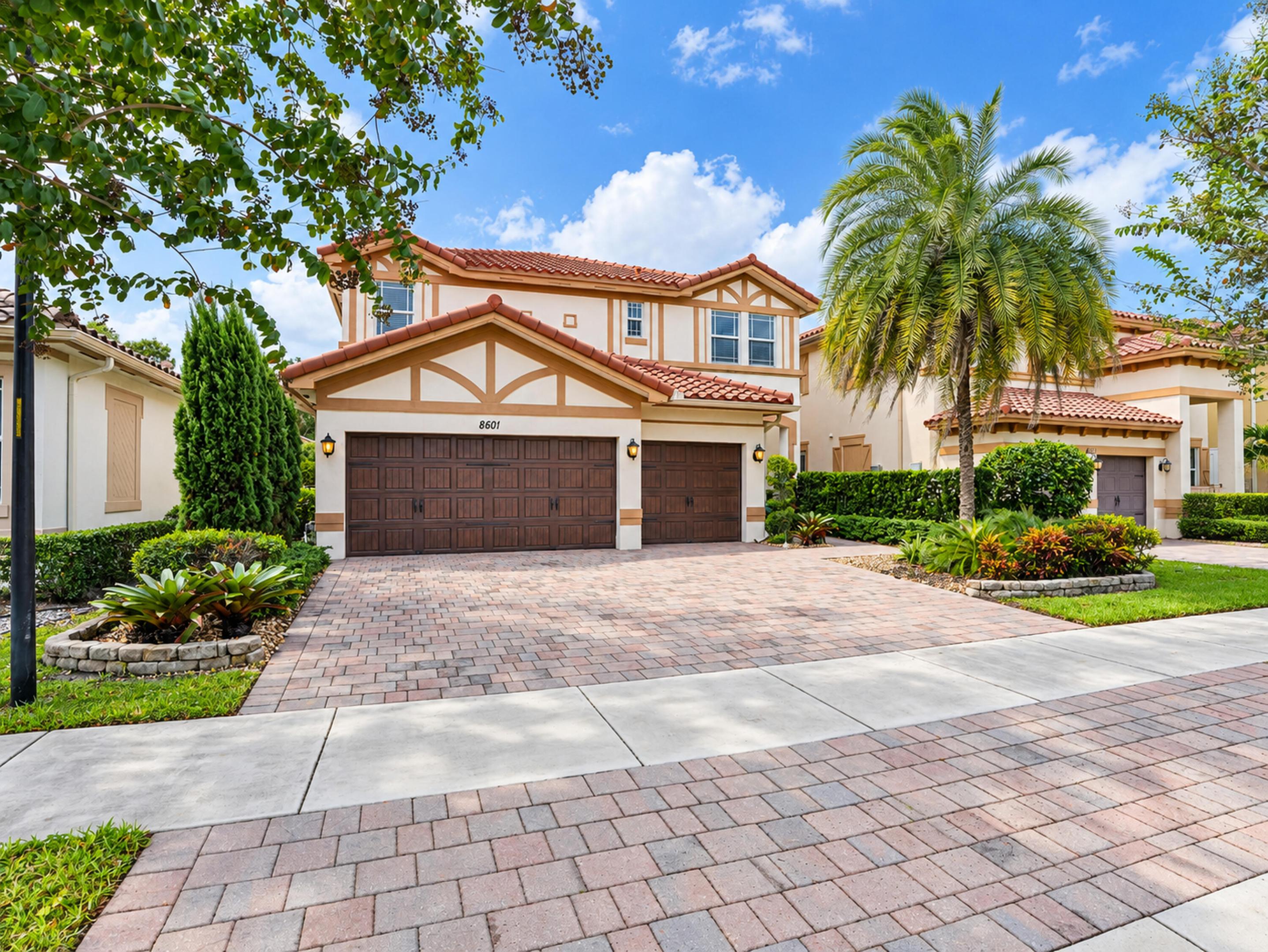 Two-story exterior featuring a tile roof, stucco finish, timber-frame detailing, and a multi-car garage with a paved driveway