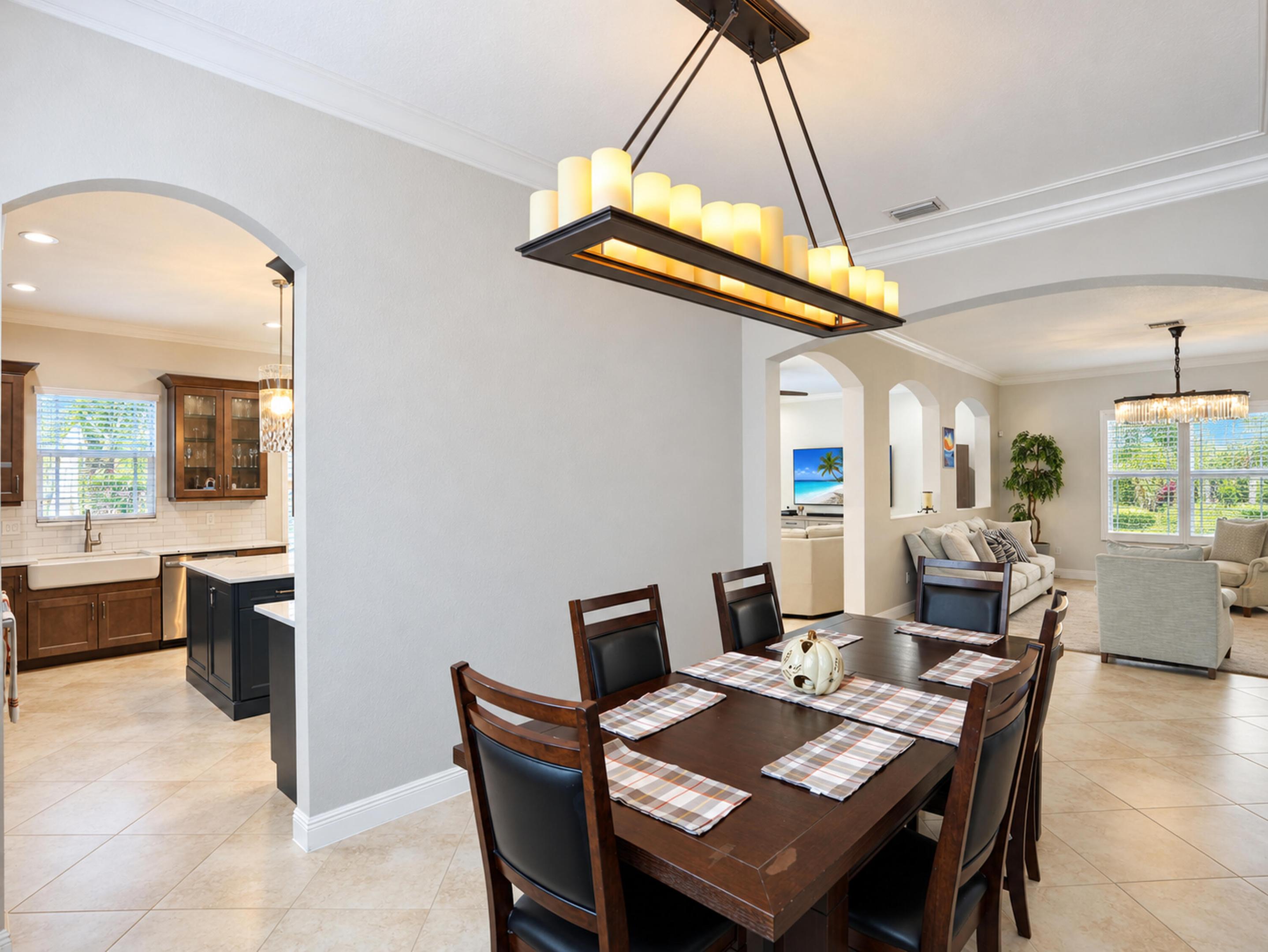 Architectural archways, candle-style rectangular chandelier, crown molding, and large-format tile flooring