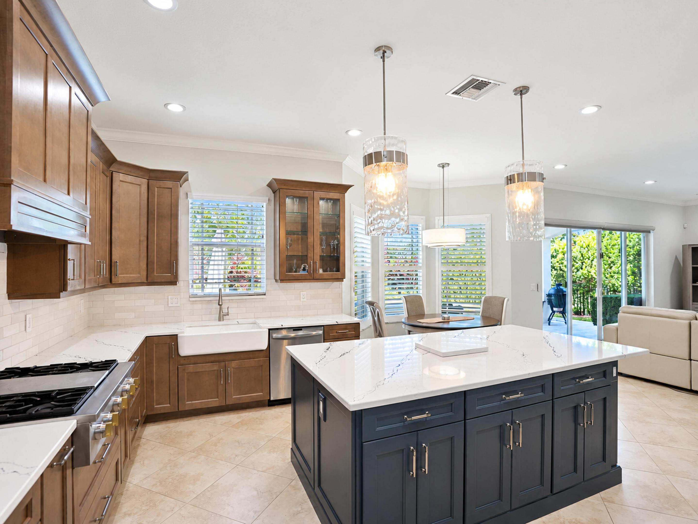 Kitchen featuring a dual-tone cabinet design, quartz countertops, a porcelain farmhouse sink, stainless steel appliances, and a large center island