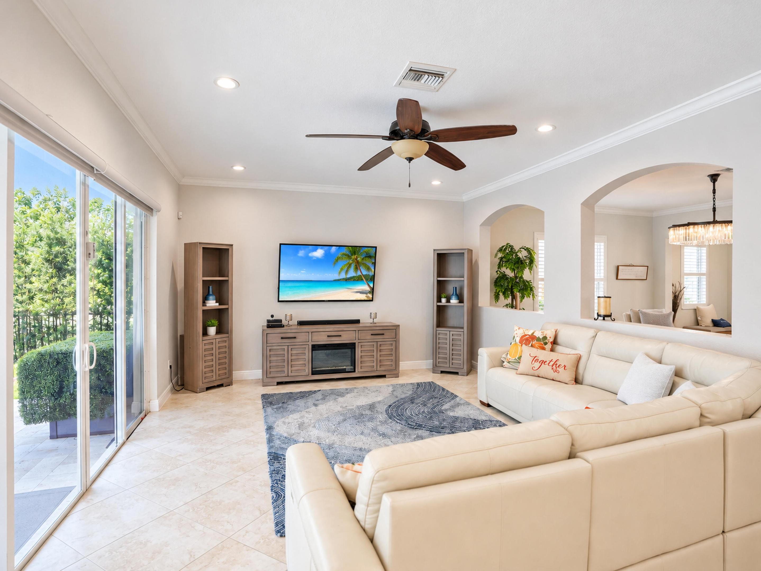 Living area featuring tile flooring, crown molding, recessed lighting, ceiling fan, and sliding glass doors