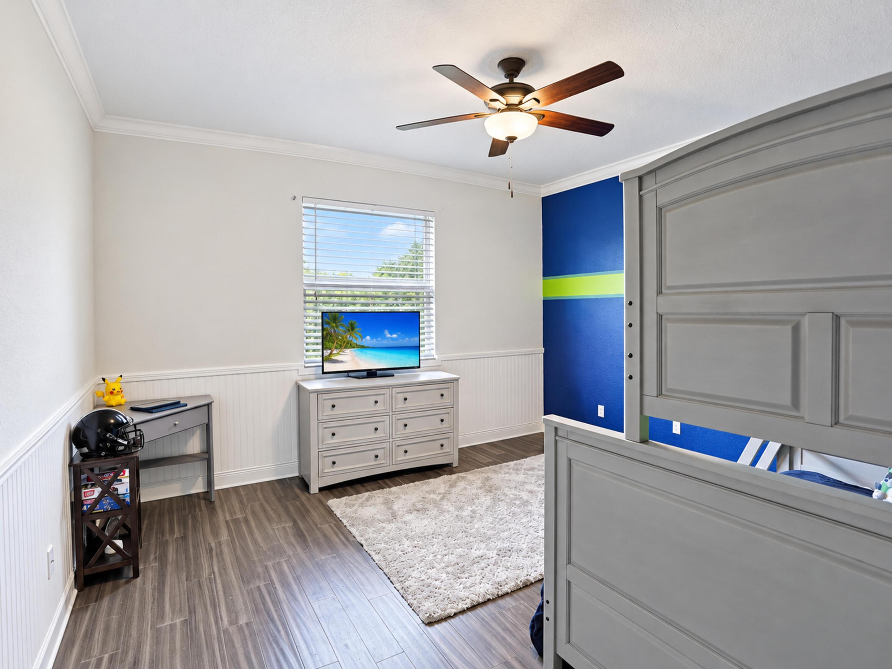 Room featuring wood-finish flooring, white wainscoting, crown molding, and a ceiling fan with integrated lighting