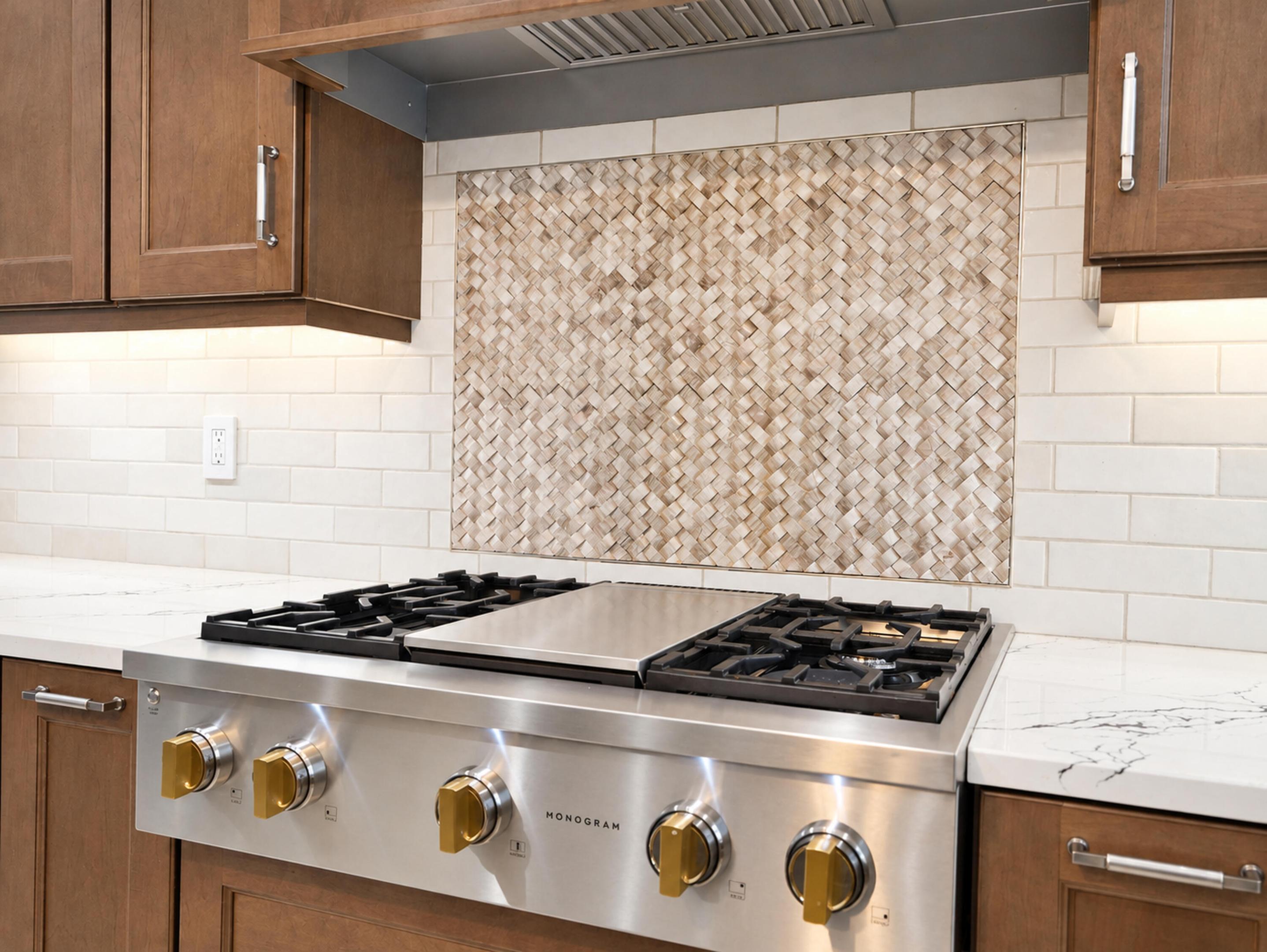 Stainless steel gas range with integrated griddle, custom basket-weave tile backsplash, light-toned stone countertops, subway tile wall accents, and stained wood cabinetry with metal hardware