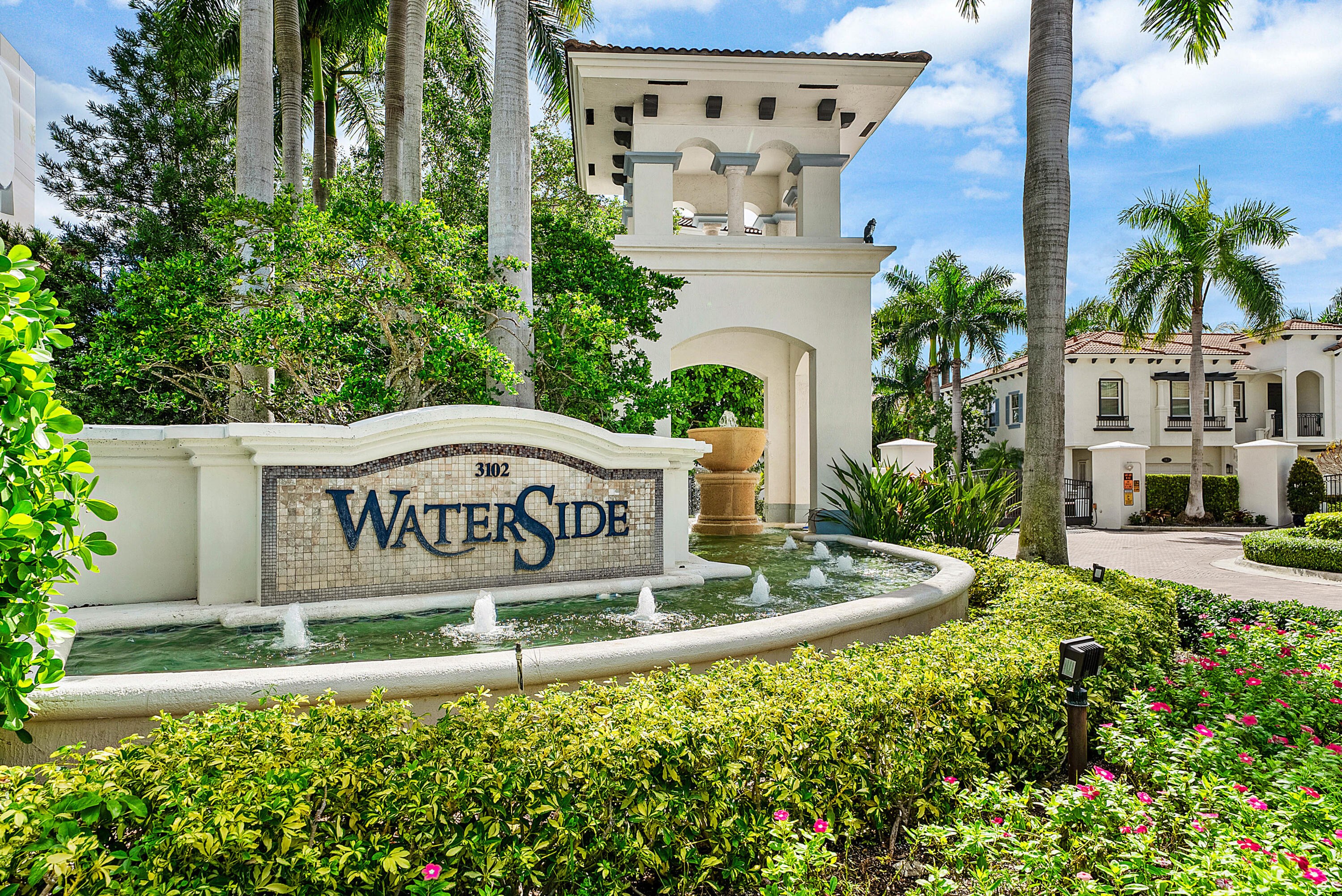 Entry monument with mosaic tile detailing, water feature with multiple fountains, and lush landscaping