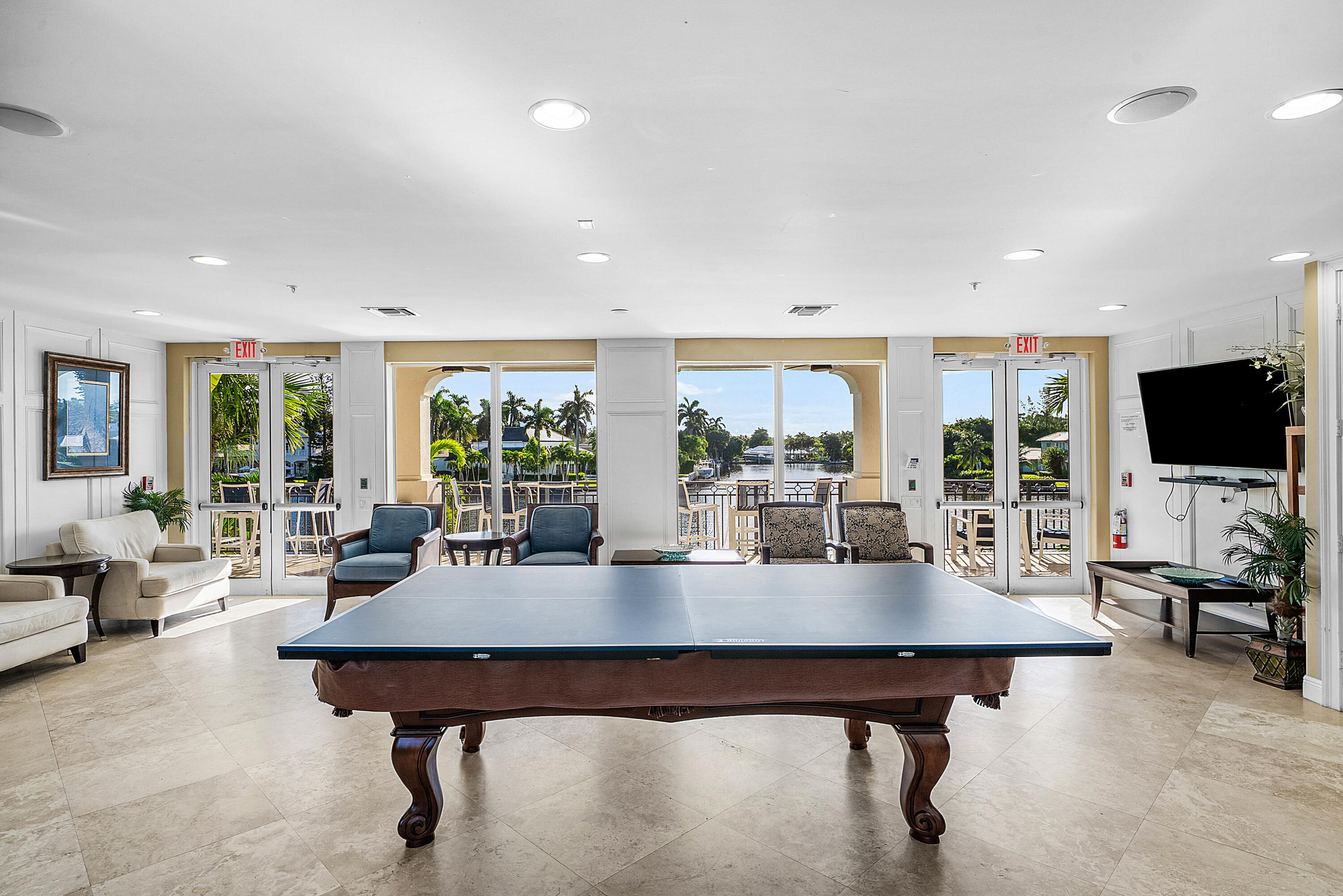 Expansive recreational space featuring a billiards table, recessed lighting, and direct access to an outdoor patio with water frontage