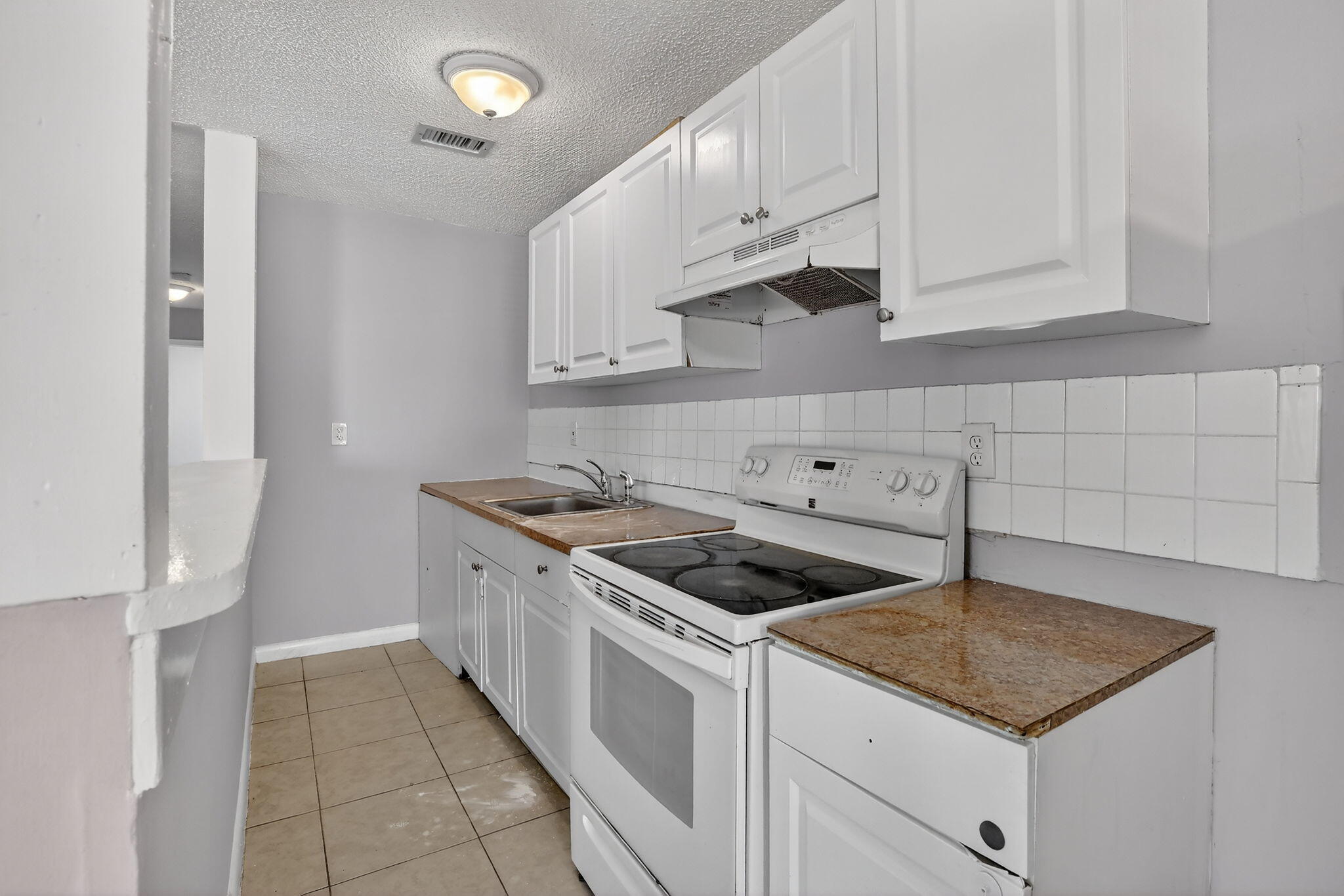 Kitchen featuring white cabinetry, stone-surface countertops, square tile backsplash, and a white electric range