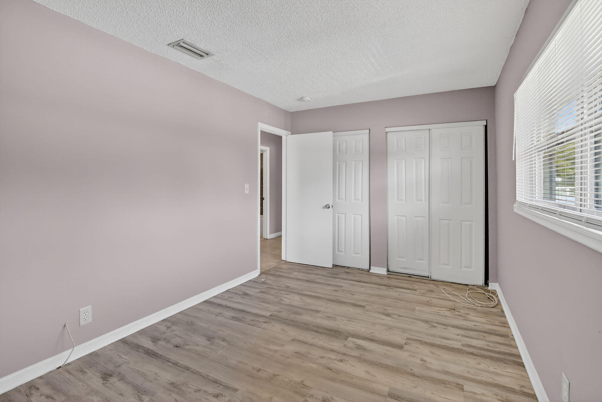 Interior room featuring wood-finish flooring, white paneled doors, and a sliding-door closet