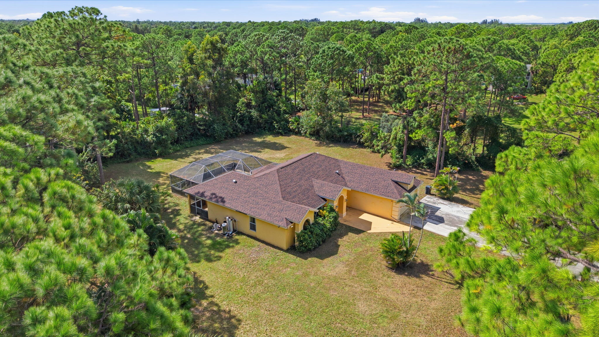 Single-story residence featuring a shingled roof, stucco exterior, attached garage, and a screened-in enclosure with a pool