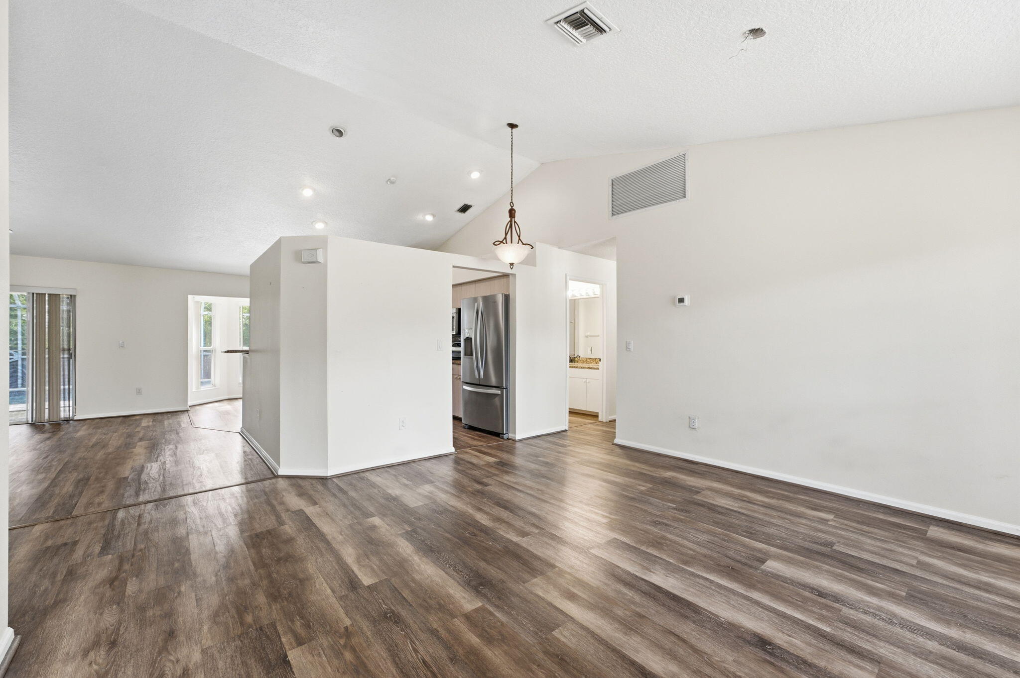 Vaulted ceilings, wood-finish flooring, stainless steel kitchen appliances, and decorative pendant lighting