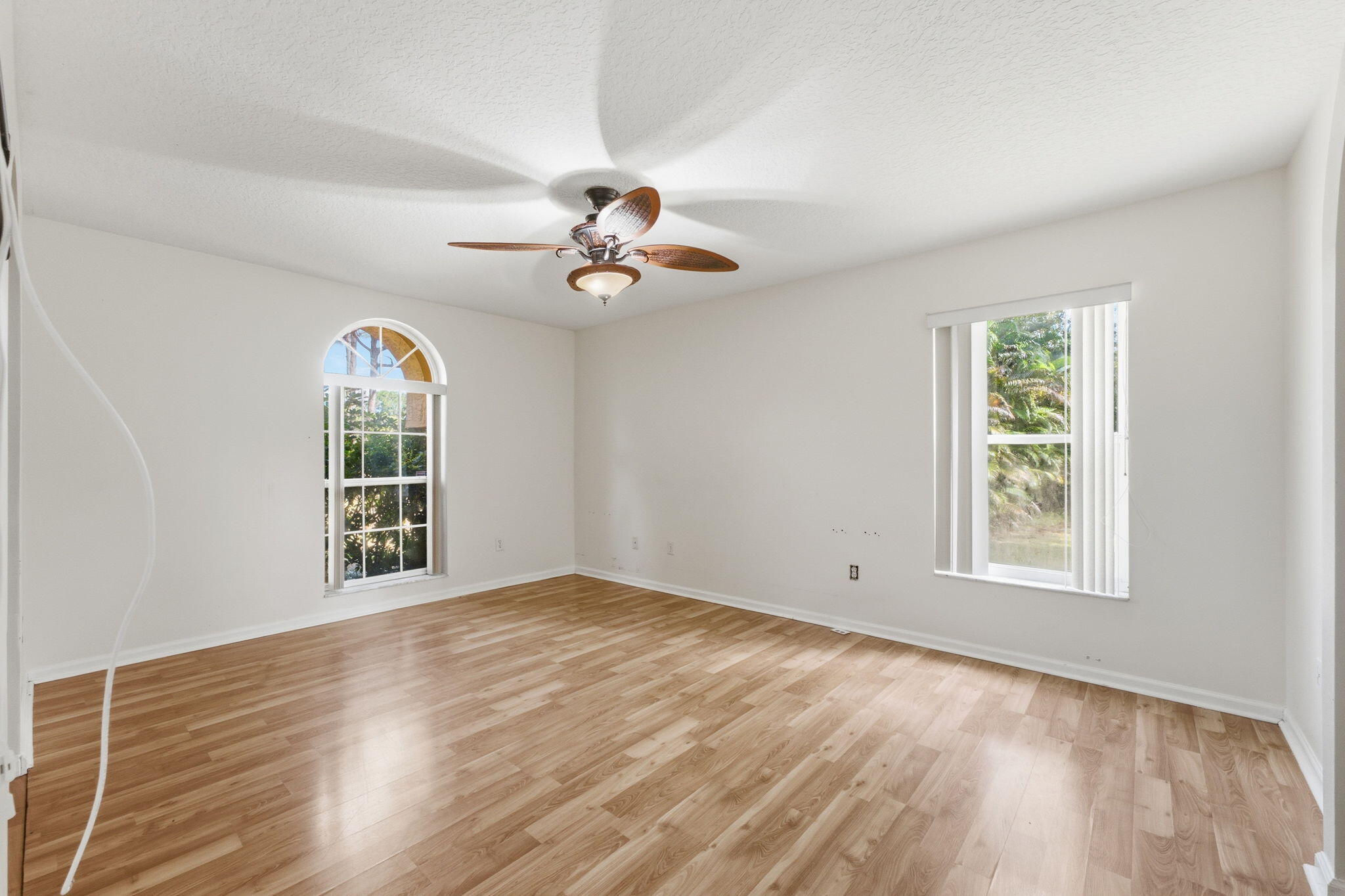 Wood-finish flooring, vaulted ceiling, arched window, and ceiling fan with integrated lighting