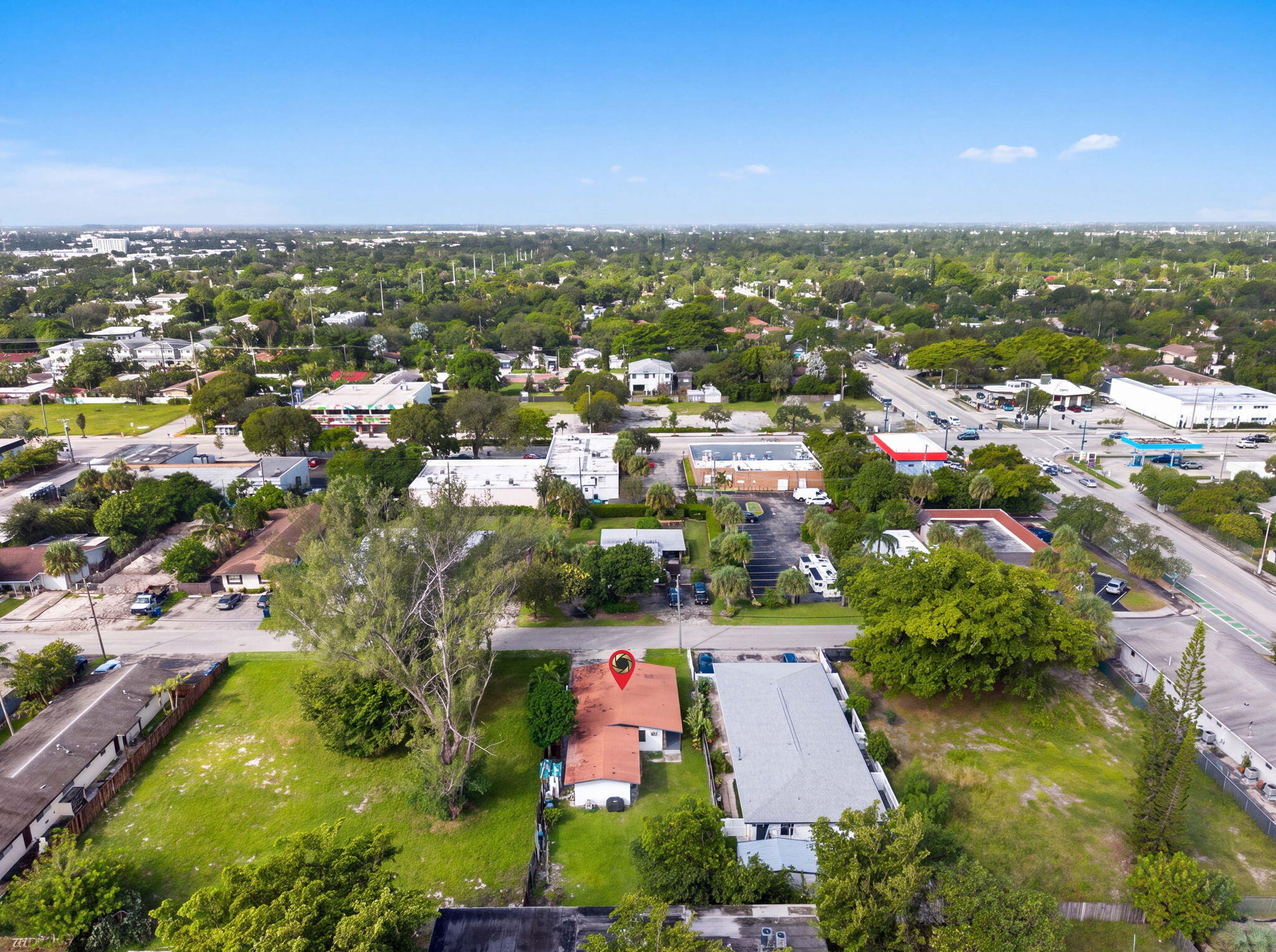 Aerial perspective featuring a single-story structure with a pitched roof, an expansive lawn, and mature trees situated on an oversized parcel
