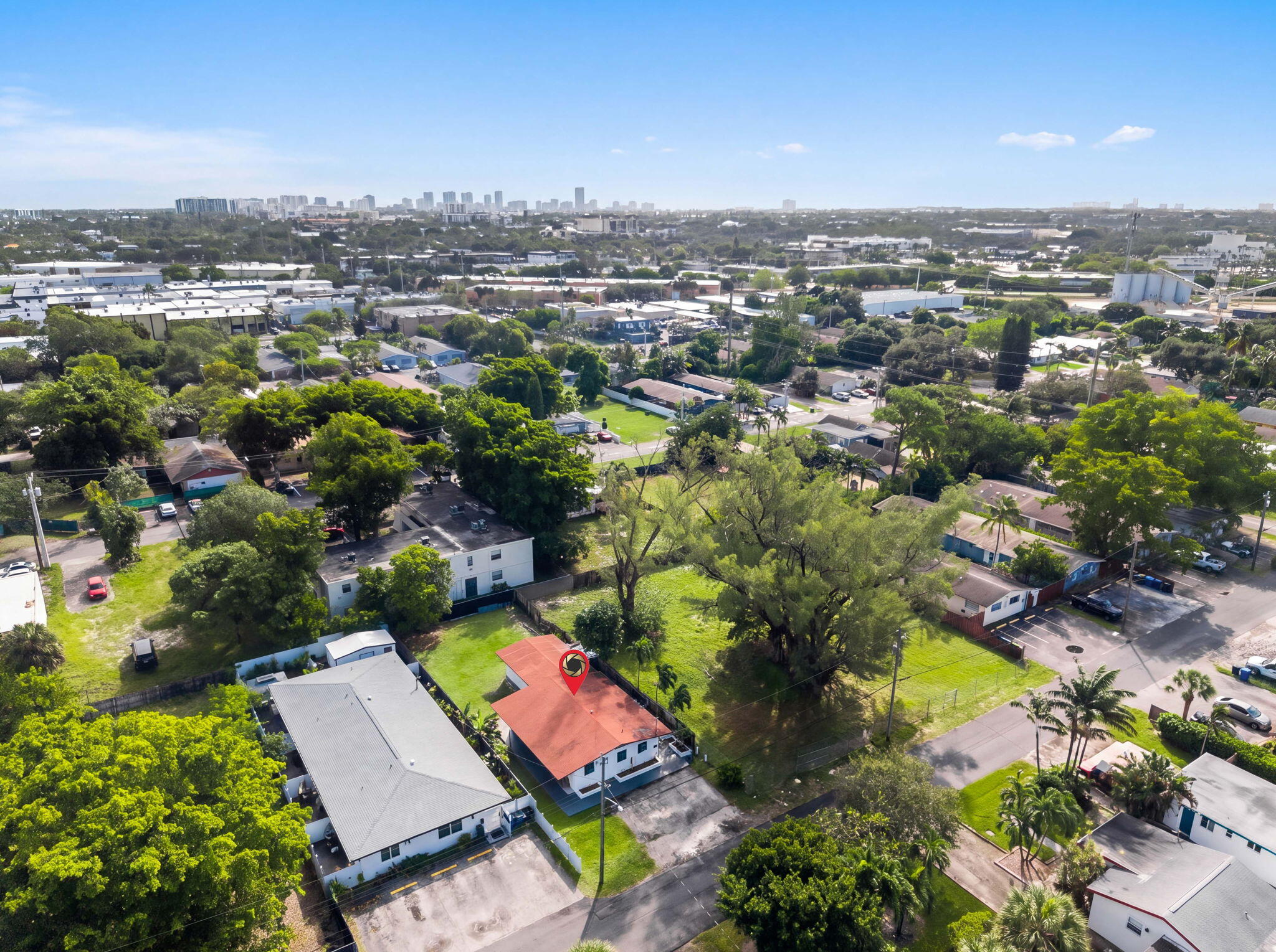 Aerial perspective of a property featuring a pitched red roof, private driveway, and mature landscaping within a suburban setting