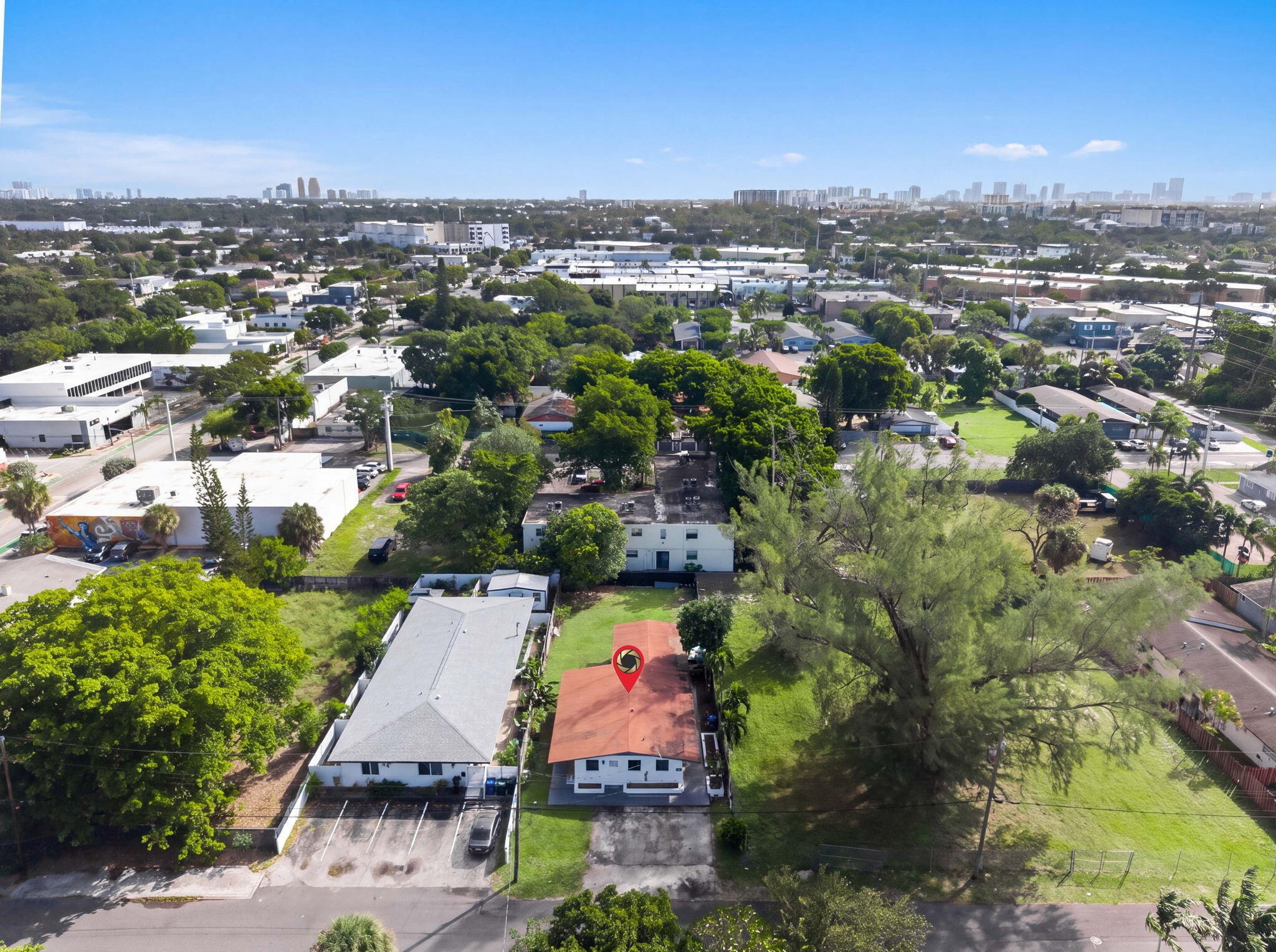 Aerial perspective of a detached property featuring a pitched roof, paved driveway, expansive lawn, and mature trees