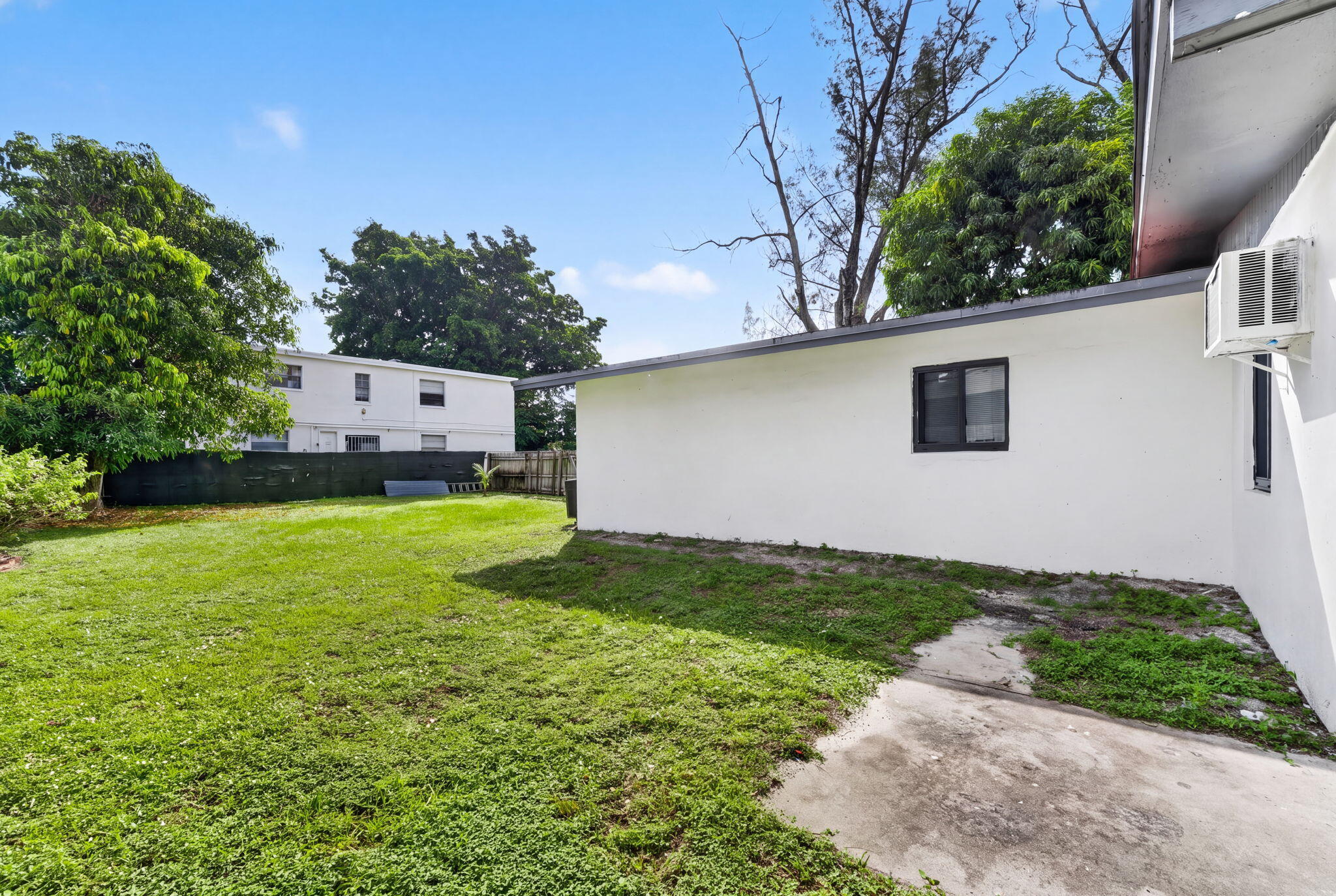 Backyard featuring a grass lawn, perimeter fencing, and concrete patio area