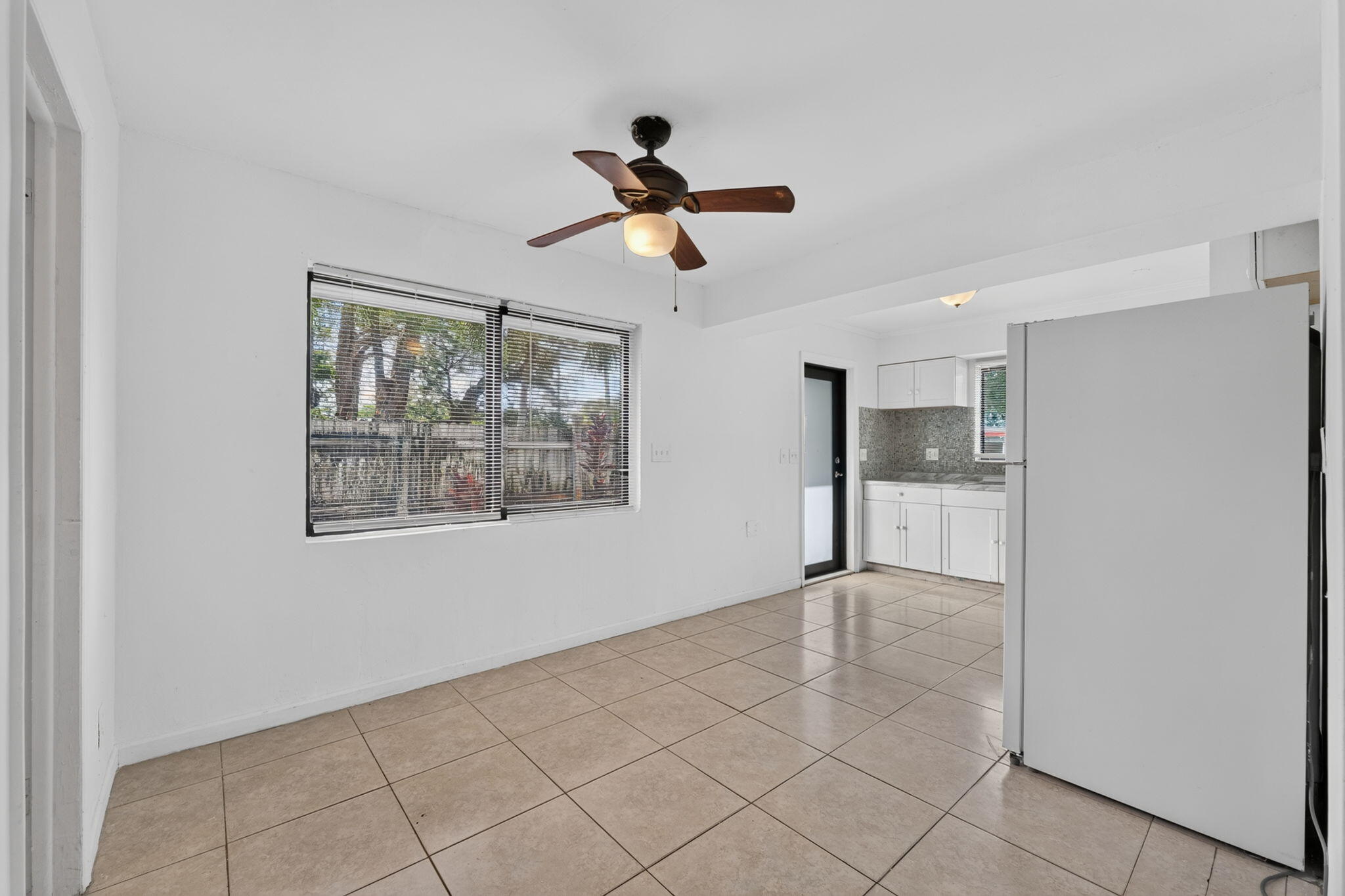 Neutral tile flooring, ceiling fan with integrated lighting, dual-pane windows, and white cabinetry