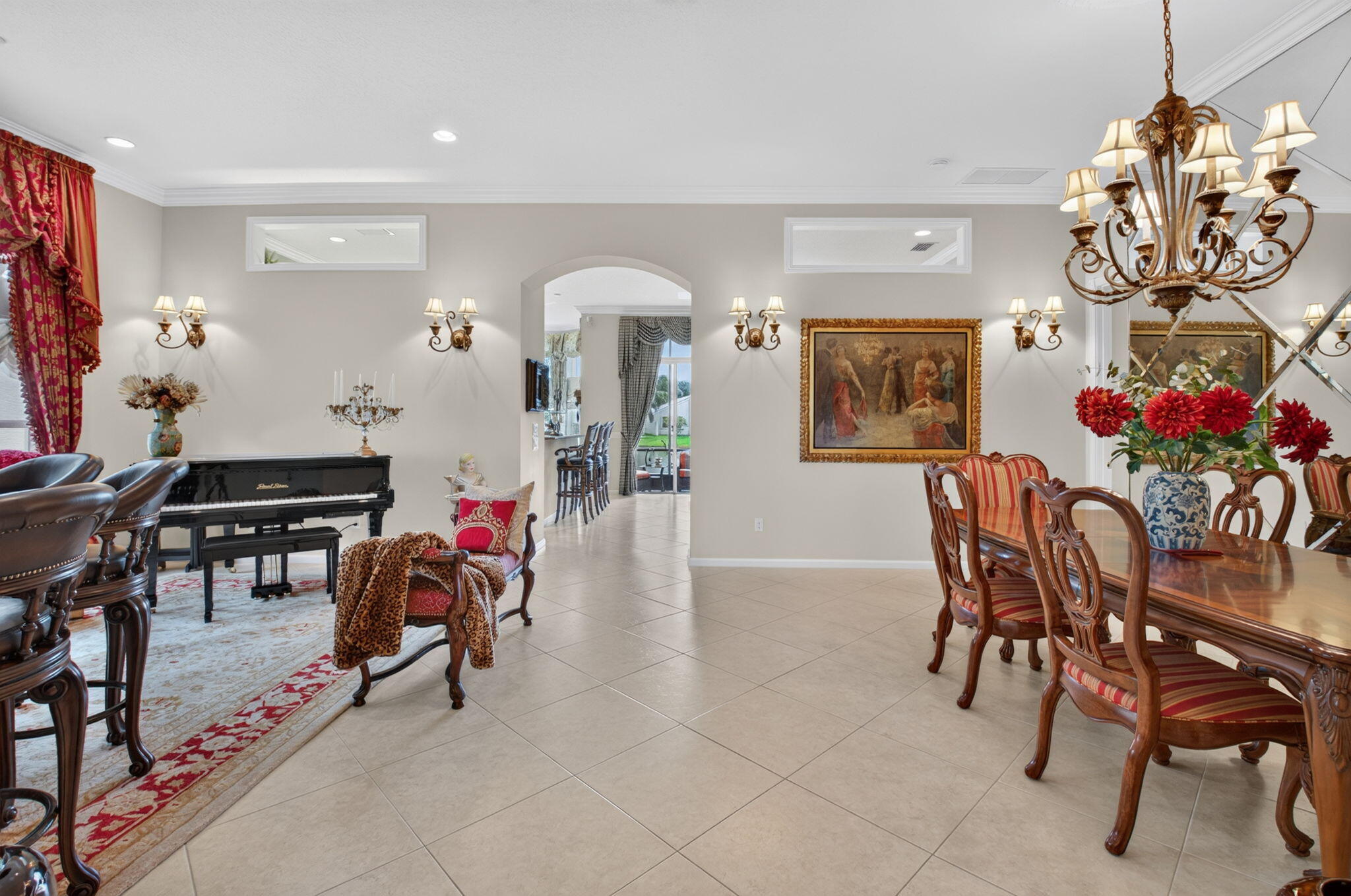 Large-format tile flooring, arched entry, transom windows, multi-arm chandelier, and mirrored wall feature
