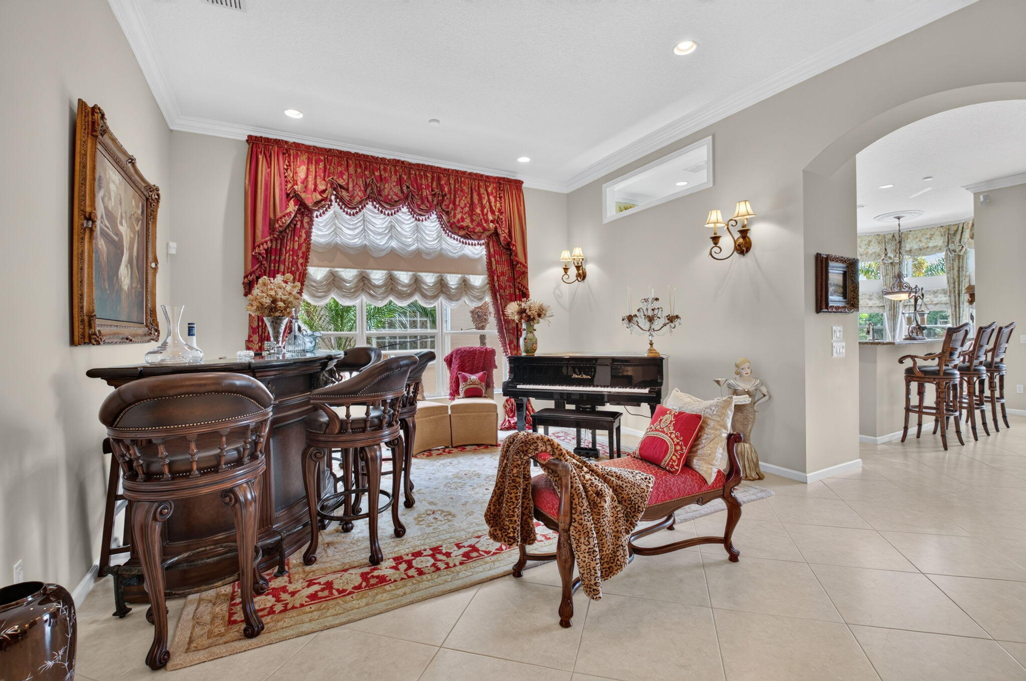 Spacious interior featuring large-format tile flooring, recessed ceiling lighting, crown molding, and two wall-mounted decorative light fixtures