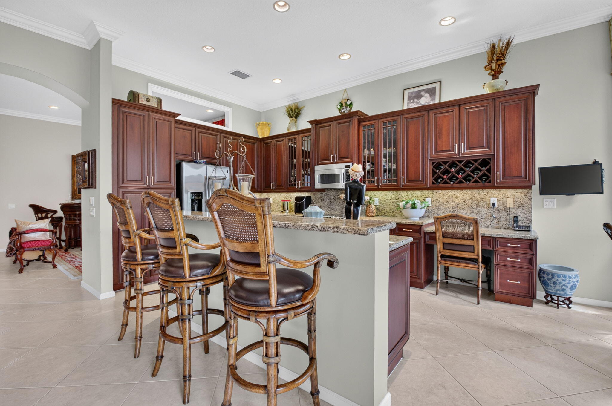 Kitchen featuring recessed lighting, stone-surface countertops, built-in cabinetry with glass-front display panels and integrated wine storage, and a breakfast bar with stone-surface top