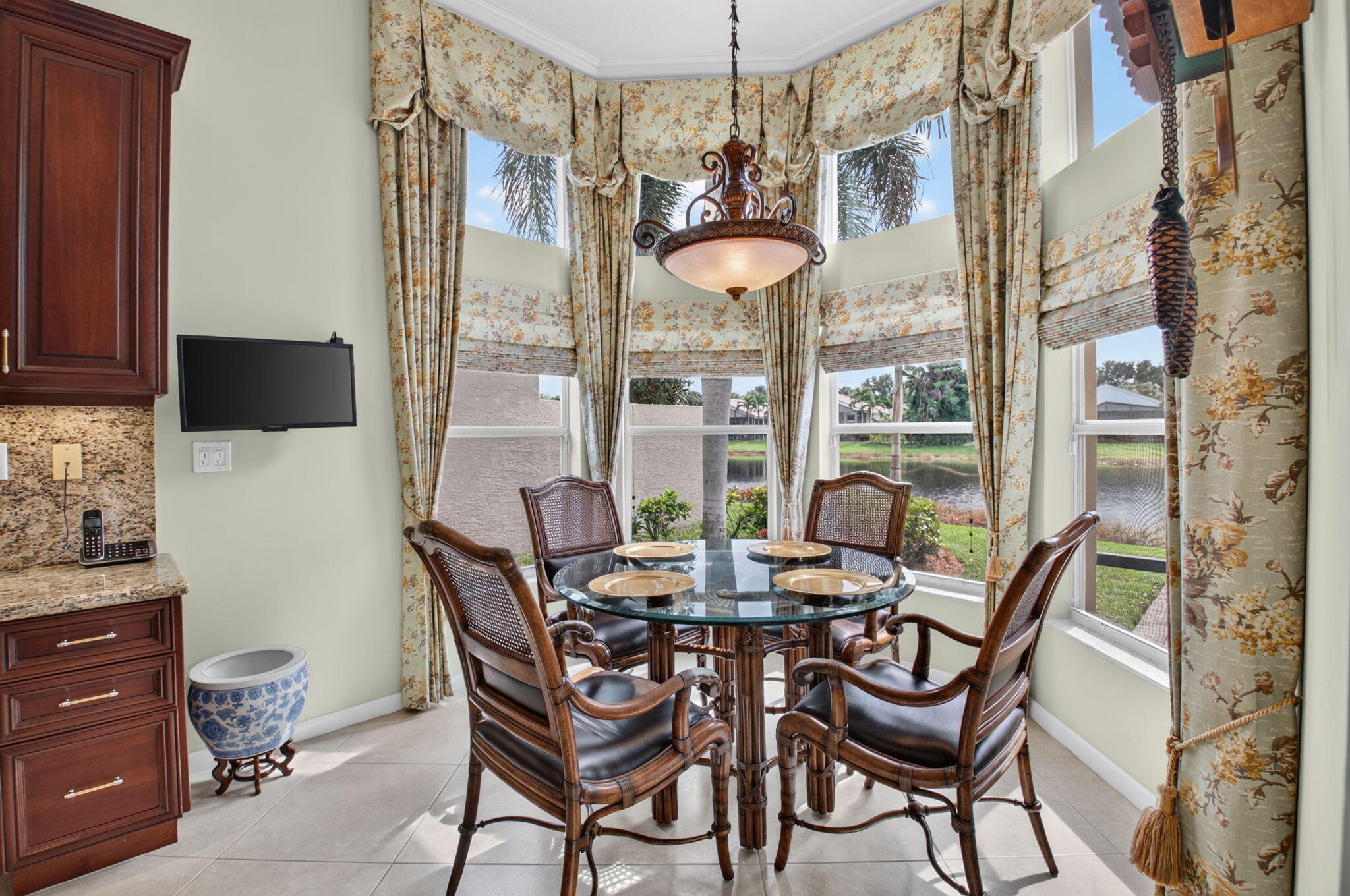 Bay window featuring expansive multi-pane glazing, stone-surfaced cabinetry, tile flooring, and a decorative pendant light fixture