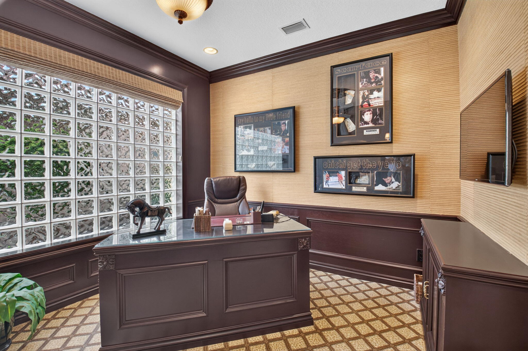 Room featuring glass block windows, grasscloth wall coverings, custom dark-toned wainscoting, intricate crown molding, and geometric tile flooring