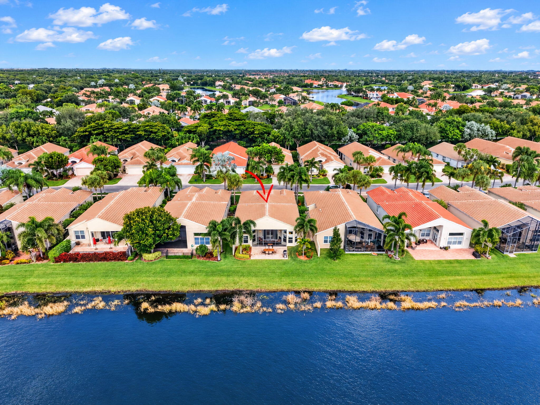 Waterfront property featuring a tile roof, covered rear patio, and expansive lawn area