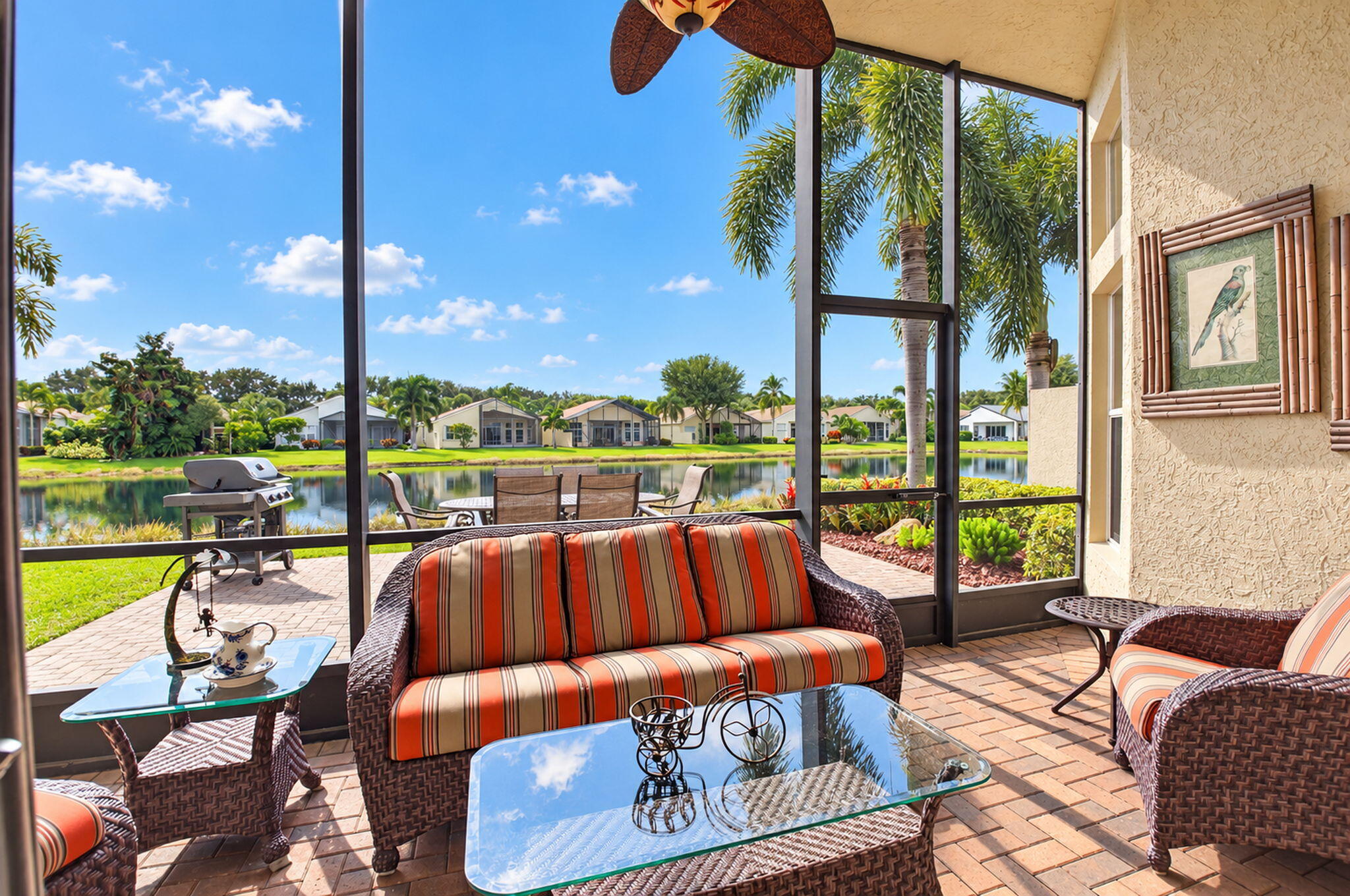 Screened-in lanai with paver flooring, overhead ceiling fan, and stucco exterior walls, featuring an expansive water frontage