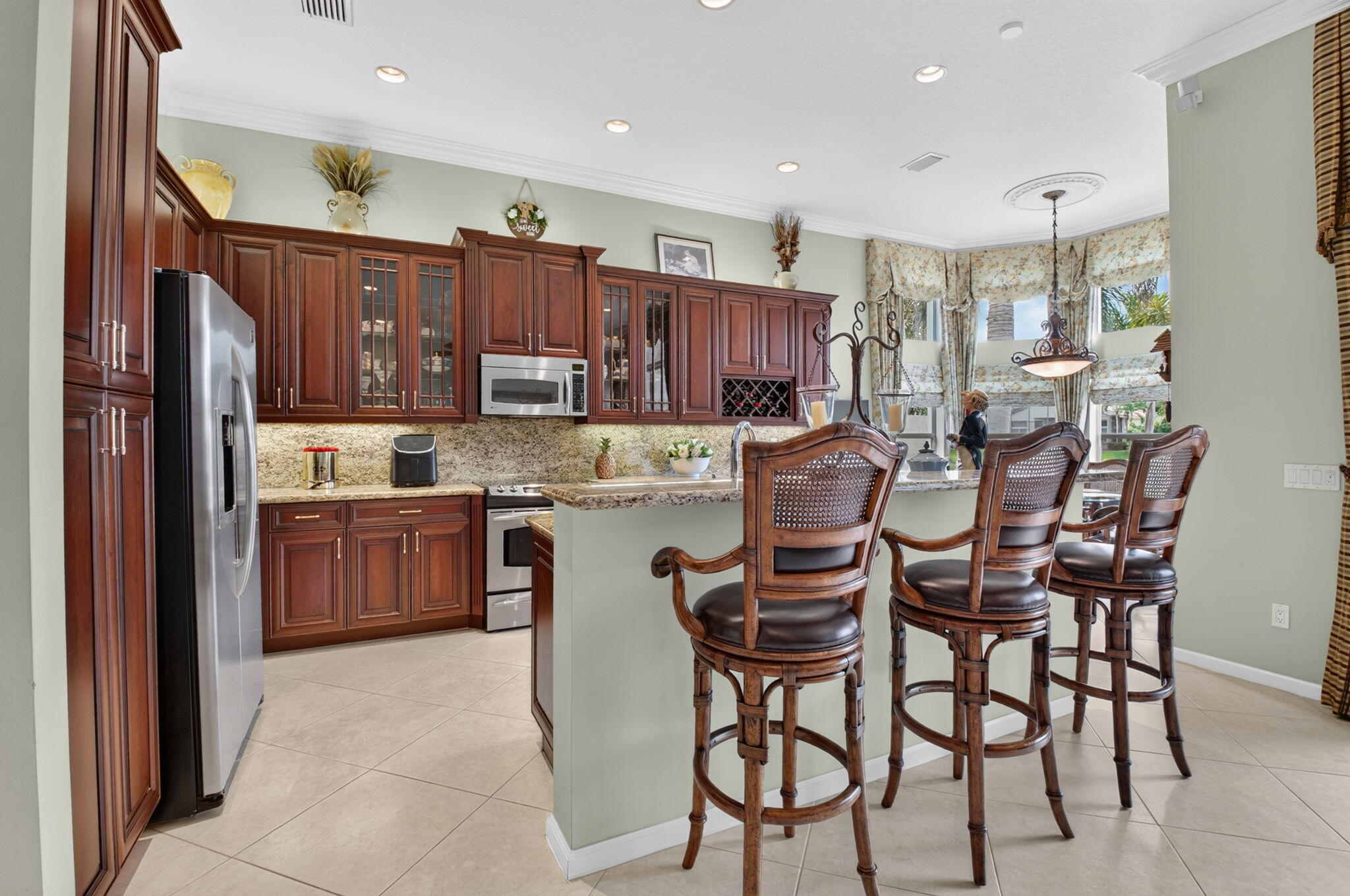 Kitchen featuring stained wood cabinetry, stone countertops, stainless steel appliances, a built-in wine rack, and recessed lighting