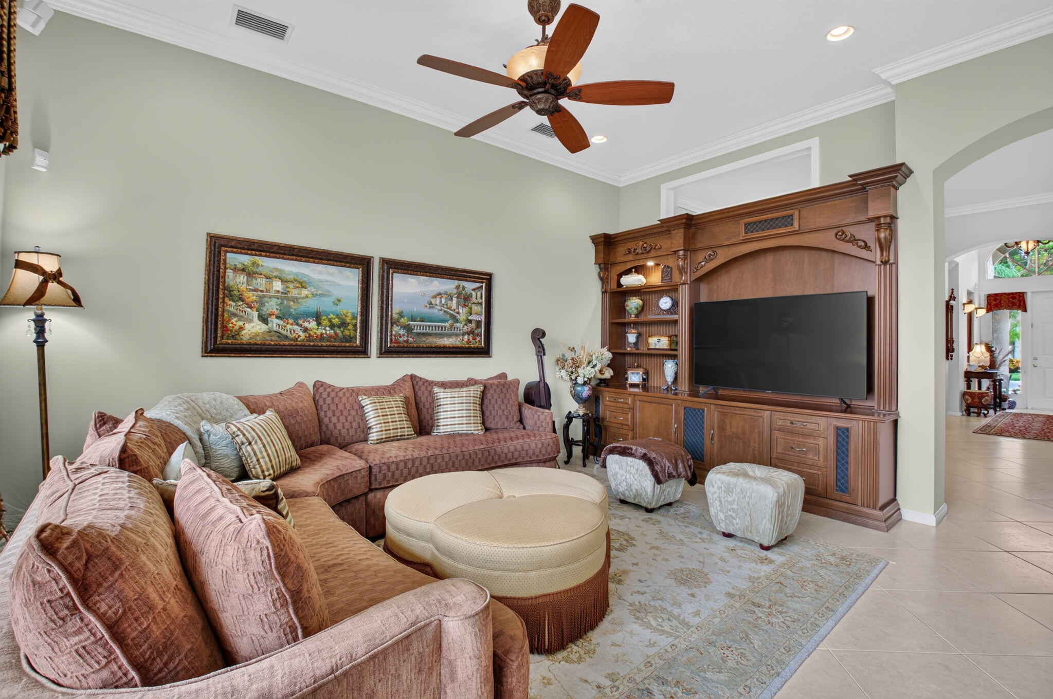 High ceilings with a central ceiling fan and custom built-in wood cabinetry featuring integrated shelving